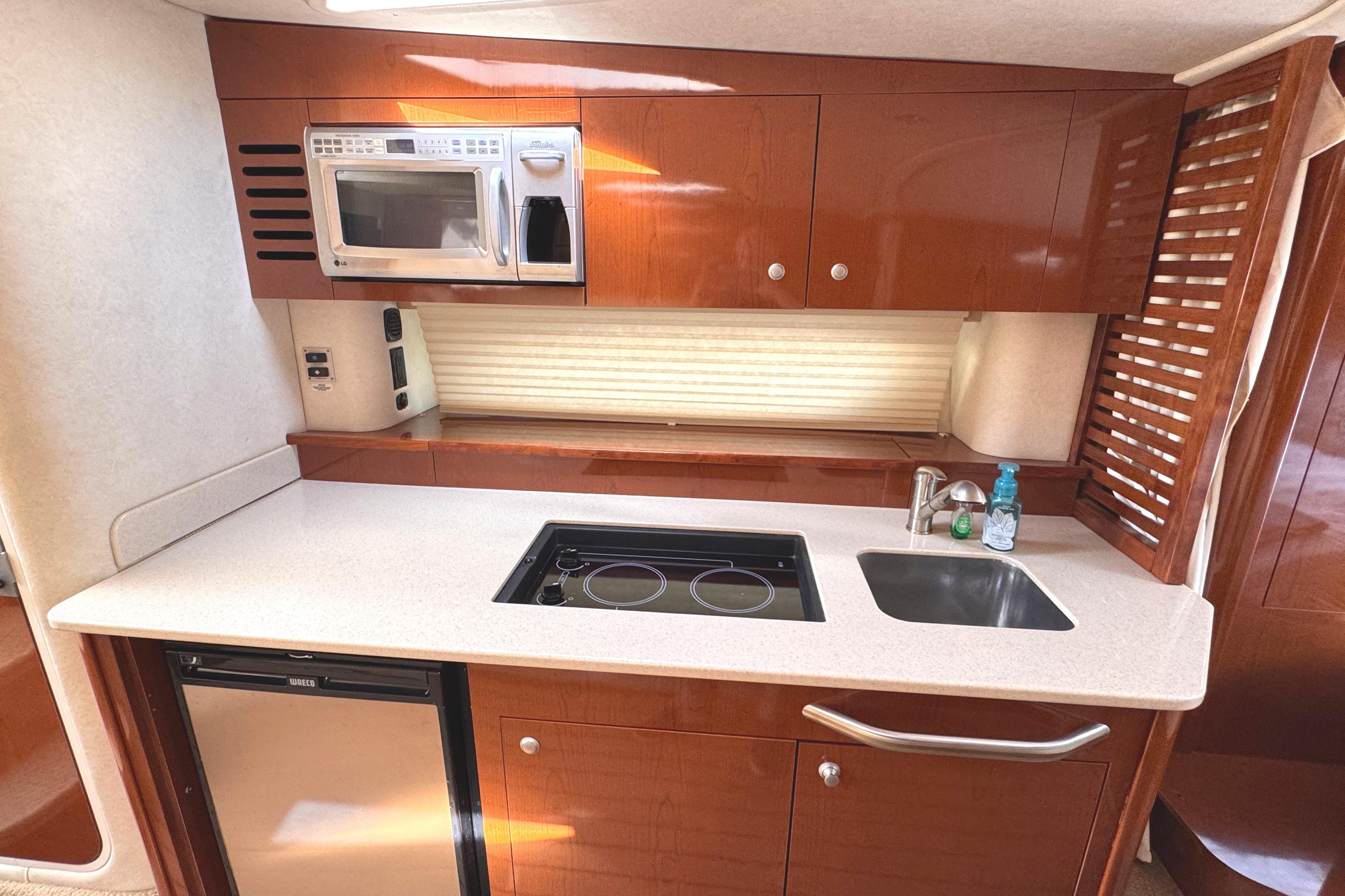 2008 Sea Ray Sundancer 350 galley with microwave, stove, sink, and compact fridge.