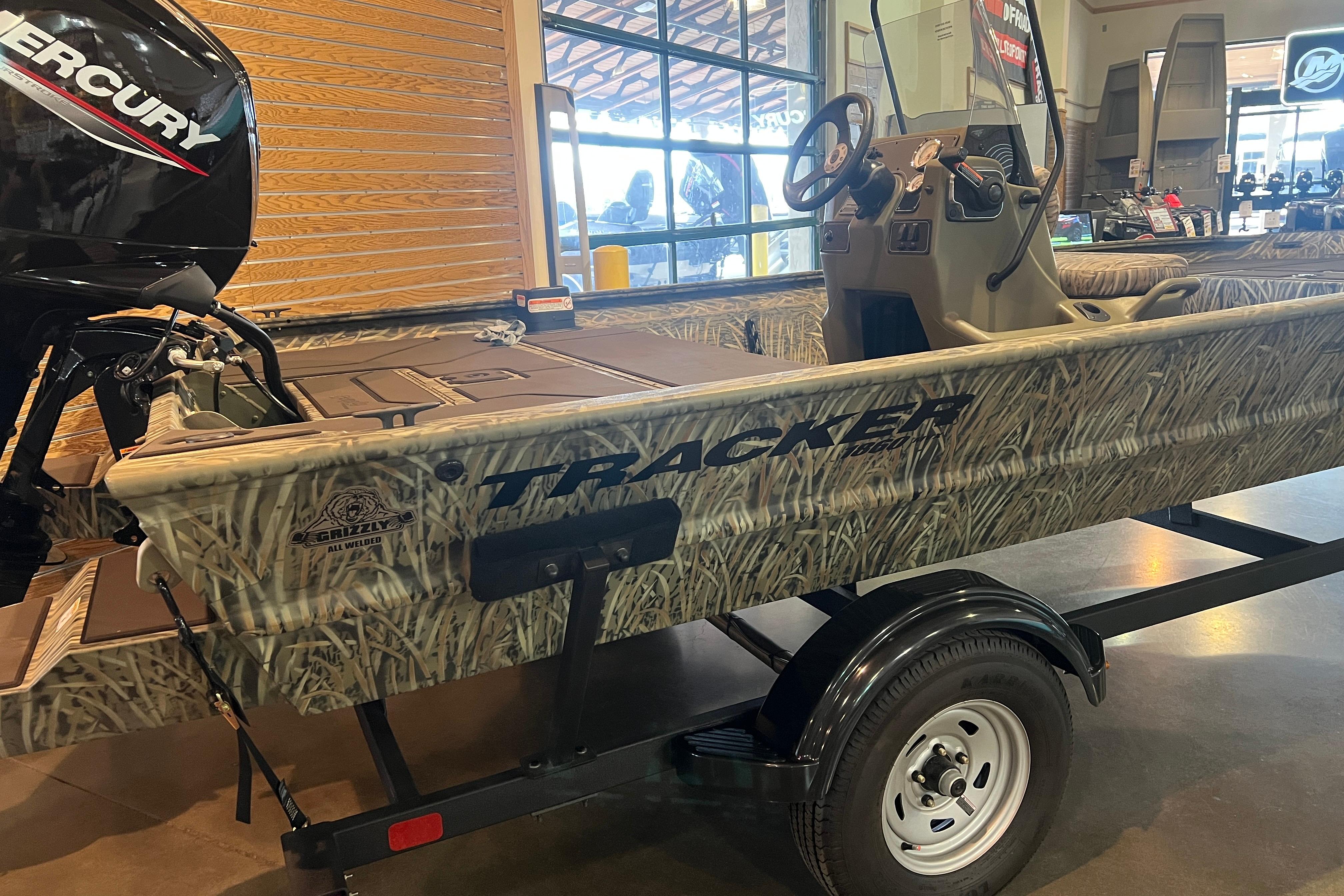 2026 Tracker Grizzly 1860 CC boat with camouflage design on display indoors.