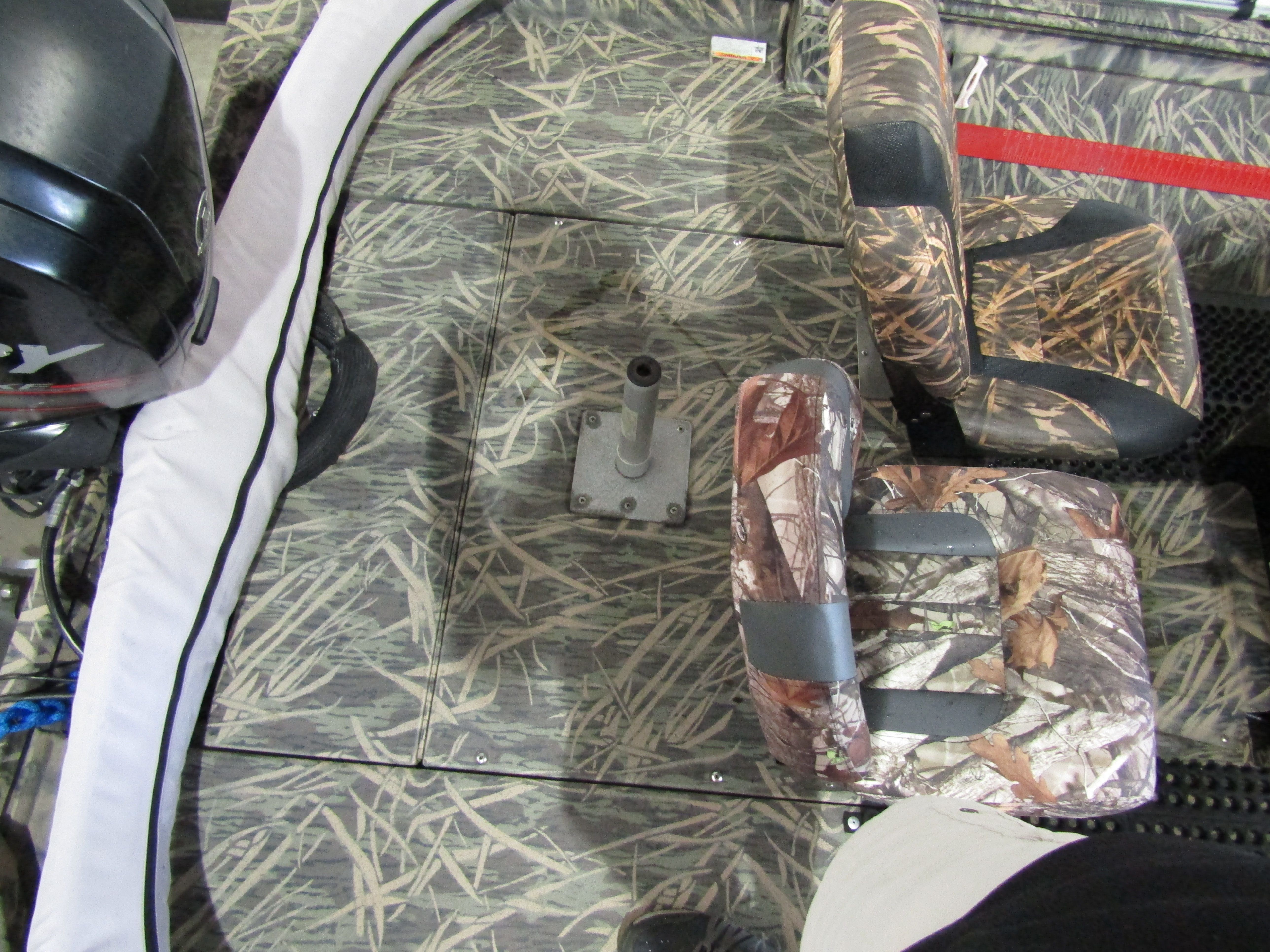 Interior view of a boat with camouflage-patterned seats and a motor in the background.