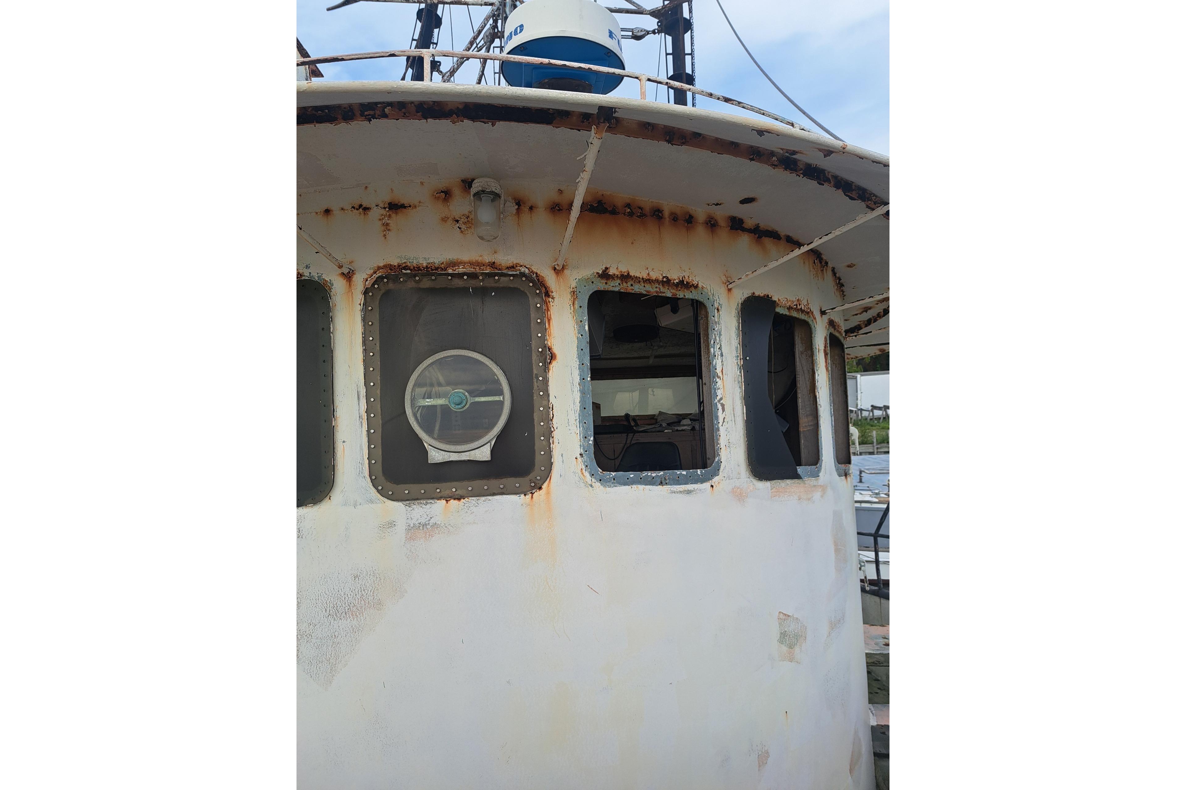 Rusty 1979 Custom Steel Trawler Dragger with weathered windows and visible steering wheel.