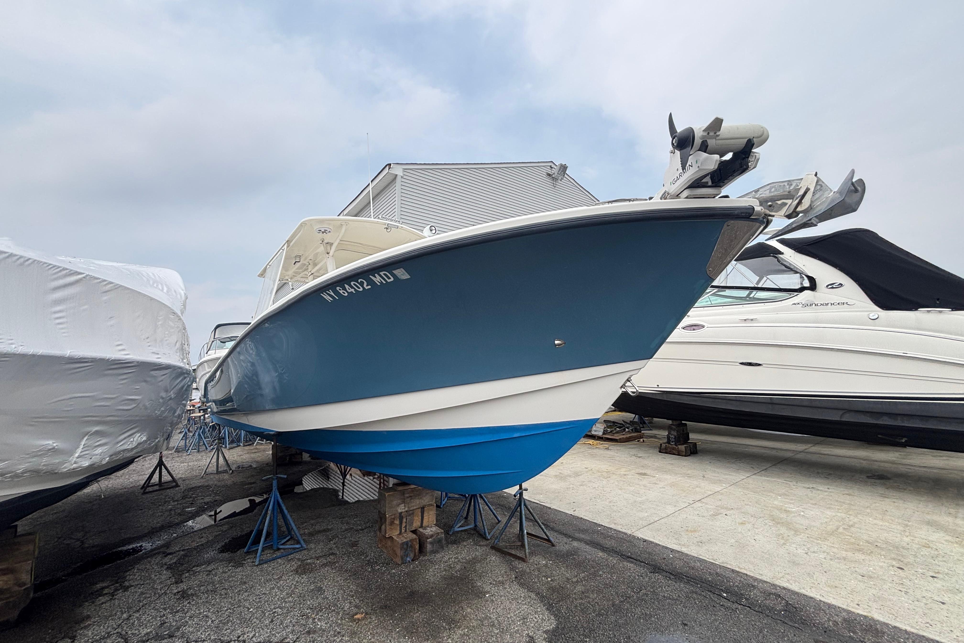 2006 Edgewater 318CC boat in storage, blue hull, parked on stands.