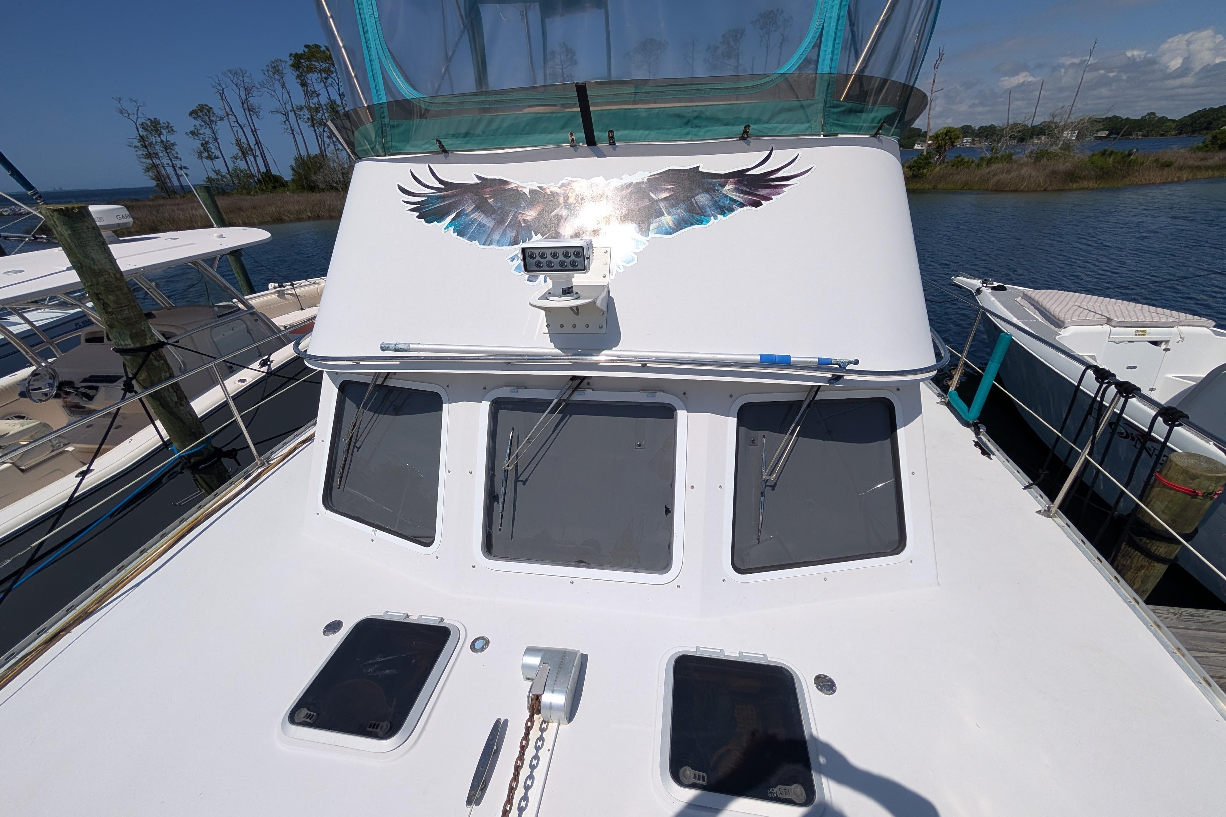 2004 PDQ 34 Powercat boat with eagle decal, docked by the water.
