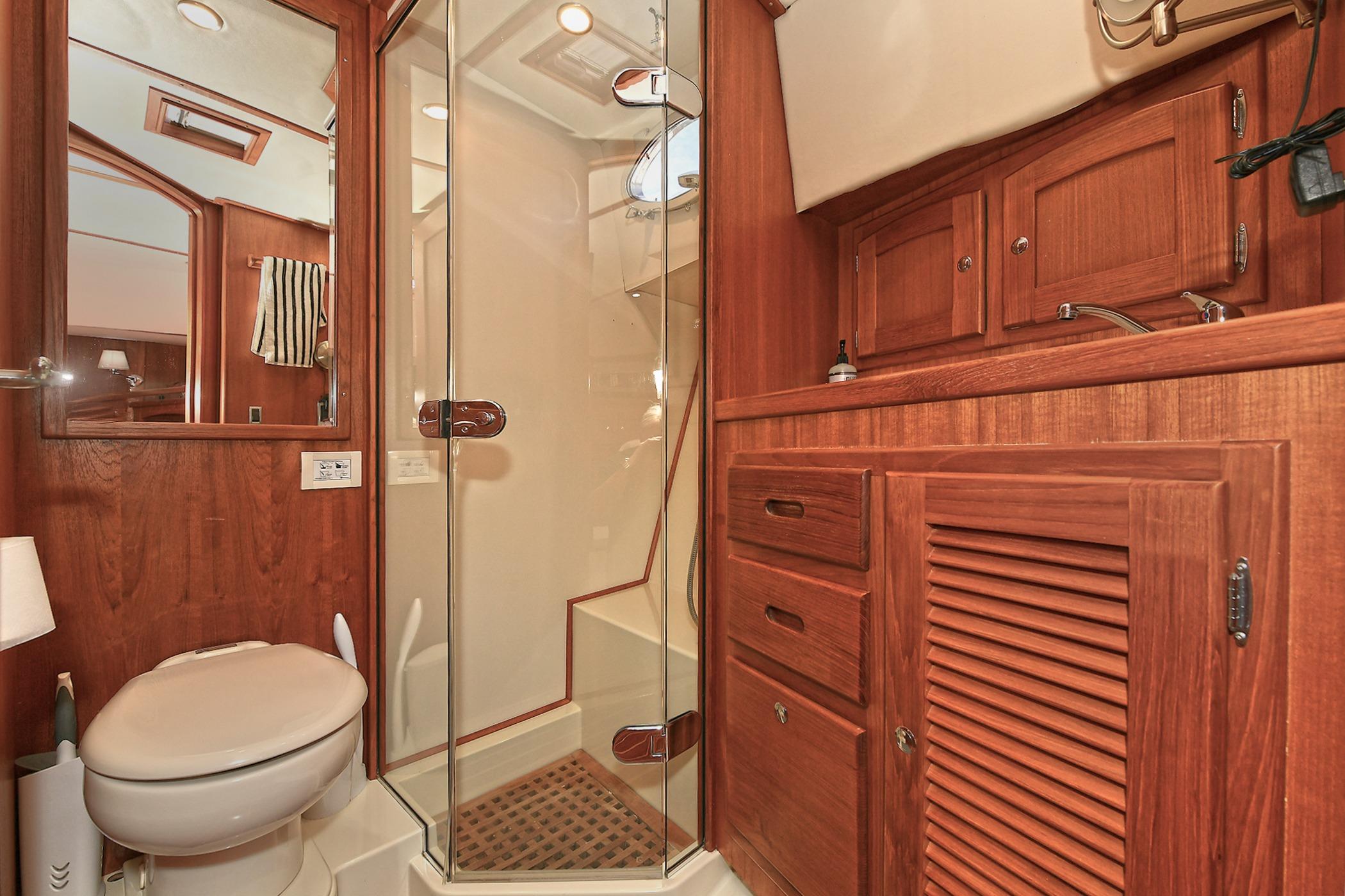 Luxurious 2005 San Juan Downeast Express yacht bathroom with wooden cabinetry and glass shower.