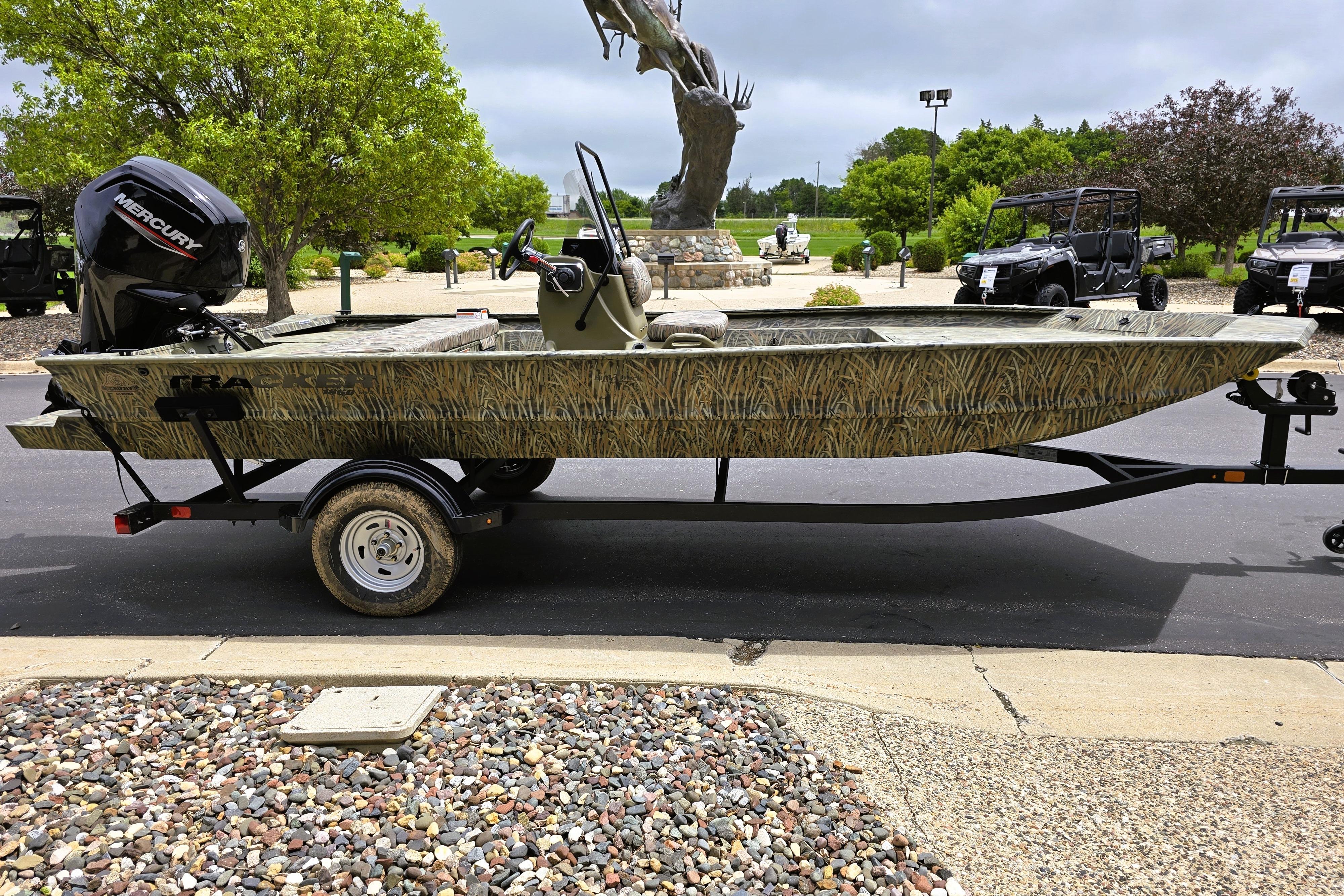 2026 Tracker Grizzly 1860 CC boat on trailer, parked outdoors with trees in background.