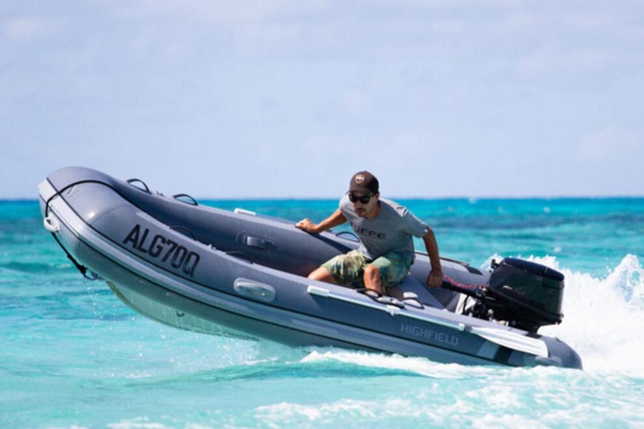 Man navigating 2025 Highfield Classic 310 inflatable boat on turquoise ocean waters.