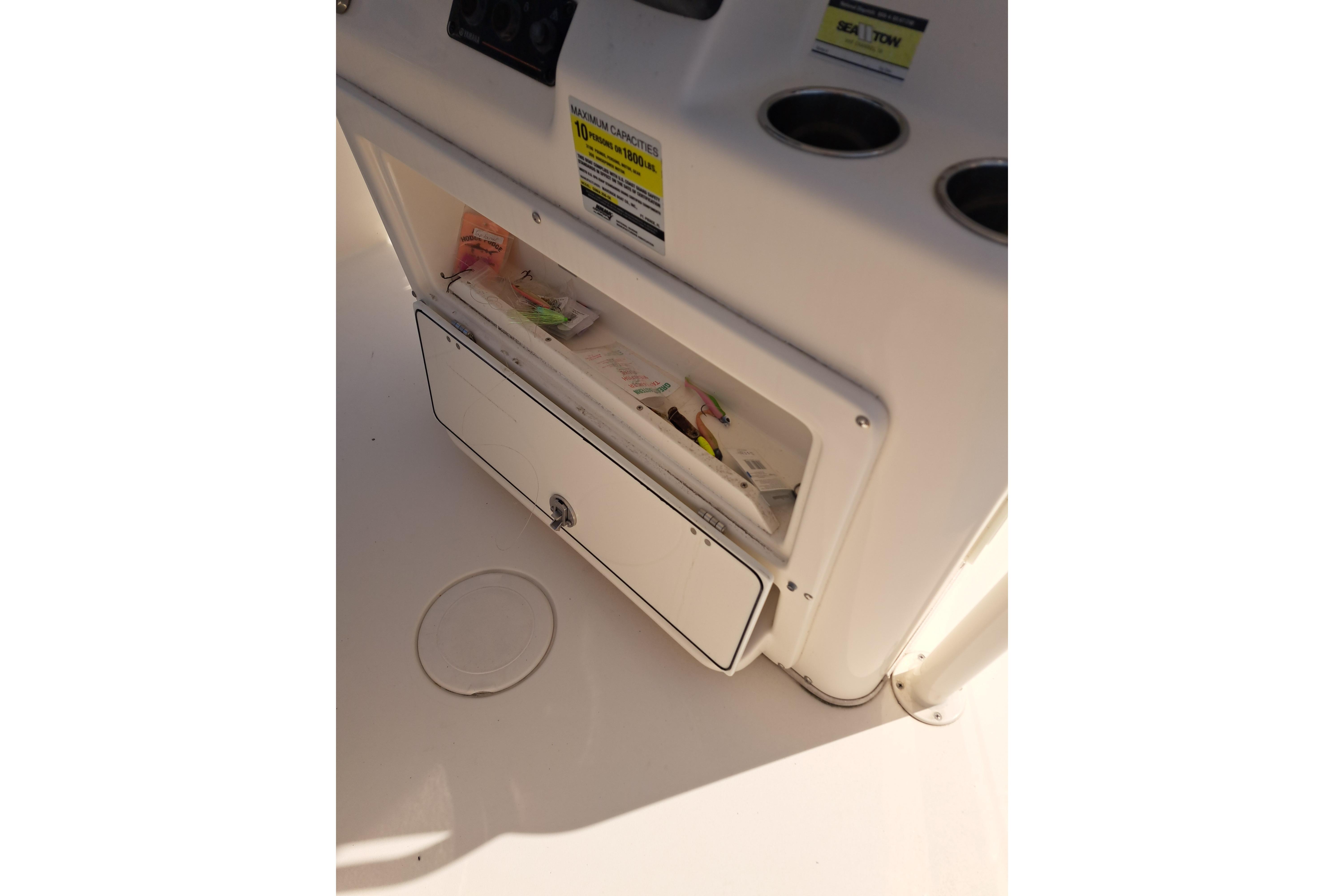 Storage compartment on a 2014 Cobia 256 Center Console boat, containing fishing gear.