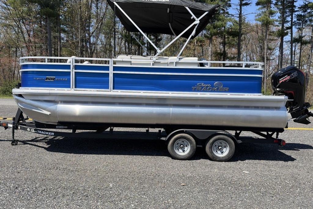 2026 Sun Tracker Fishin' Barge 20 DLX pontoon boat on trailer, parked outdoors.