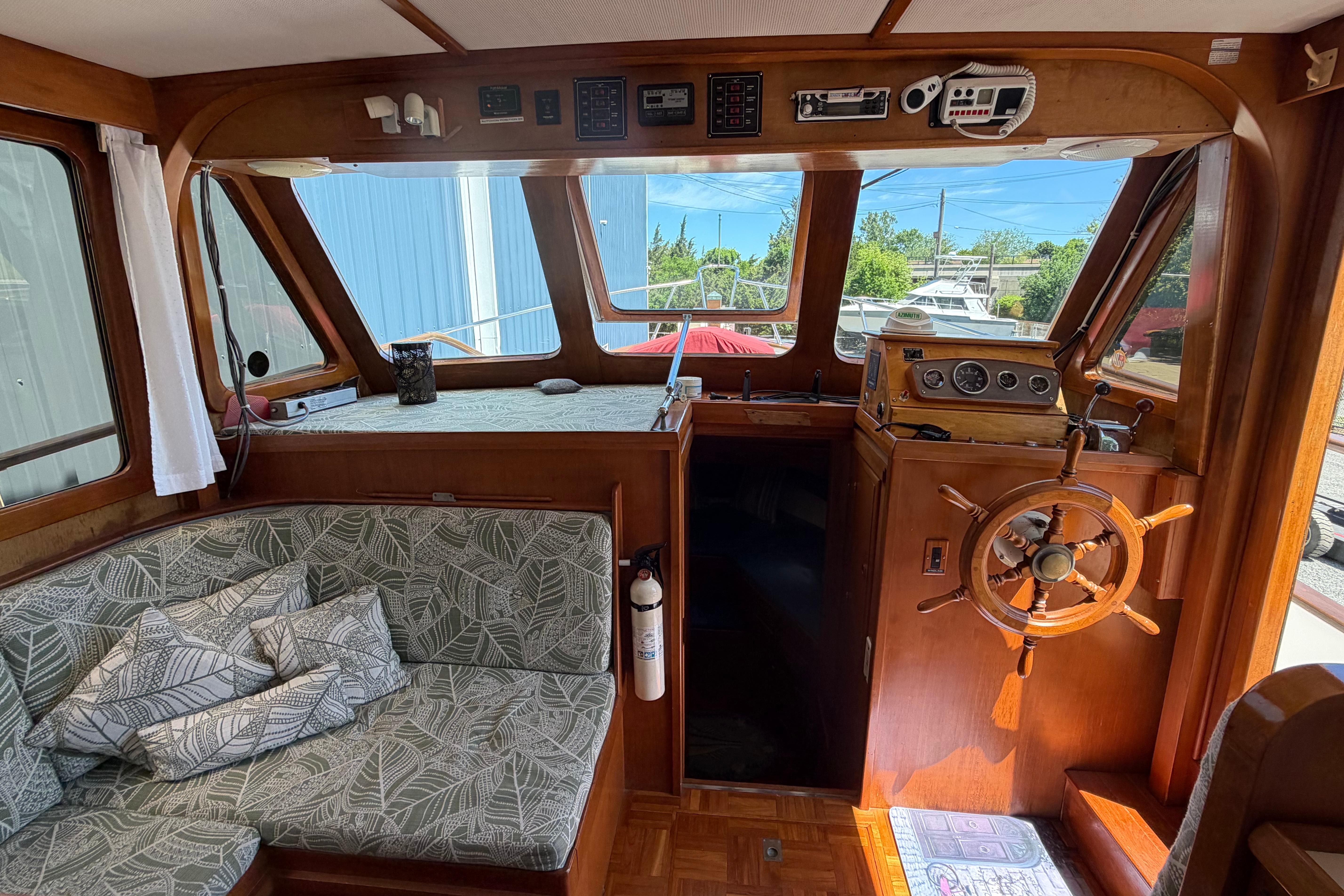 1987 Marine Trader 36 interior with wooden helm, patterned seating, and nautical decor.