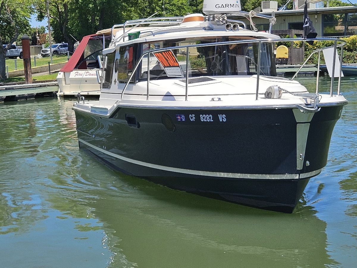 A 2020 Ranger Tugs R-23 boat is in the water, surrounded by trees and other boats.