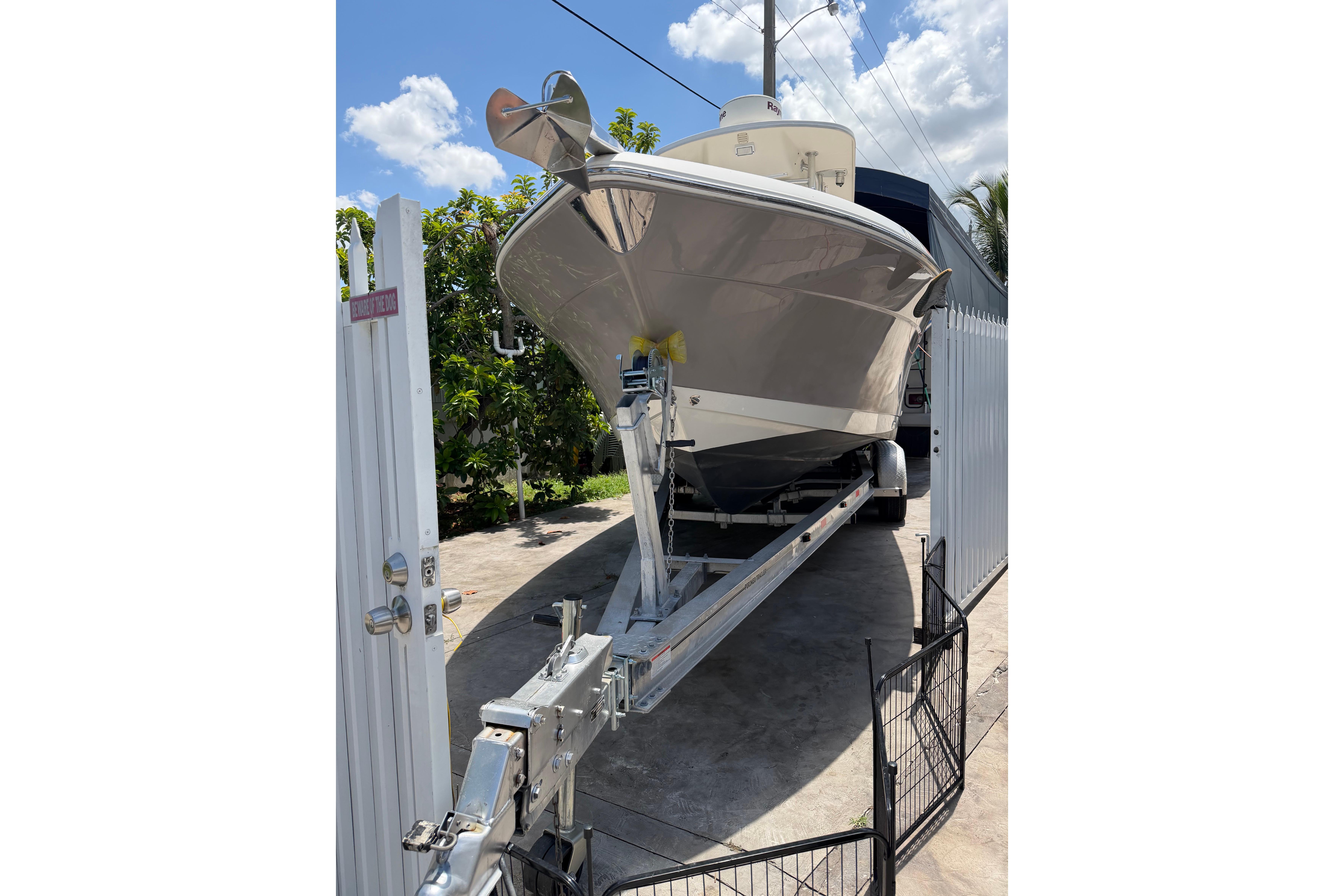 2007 Robalo R260 Center Console boat on trailer, parked in driveway under blue sky.