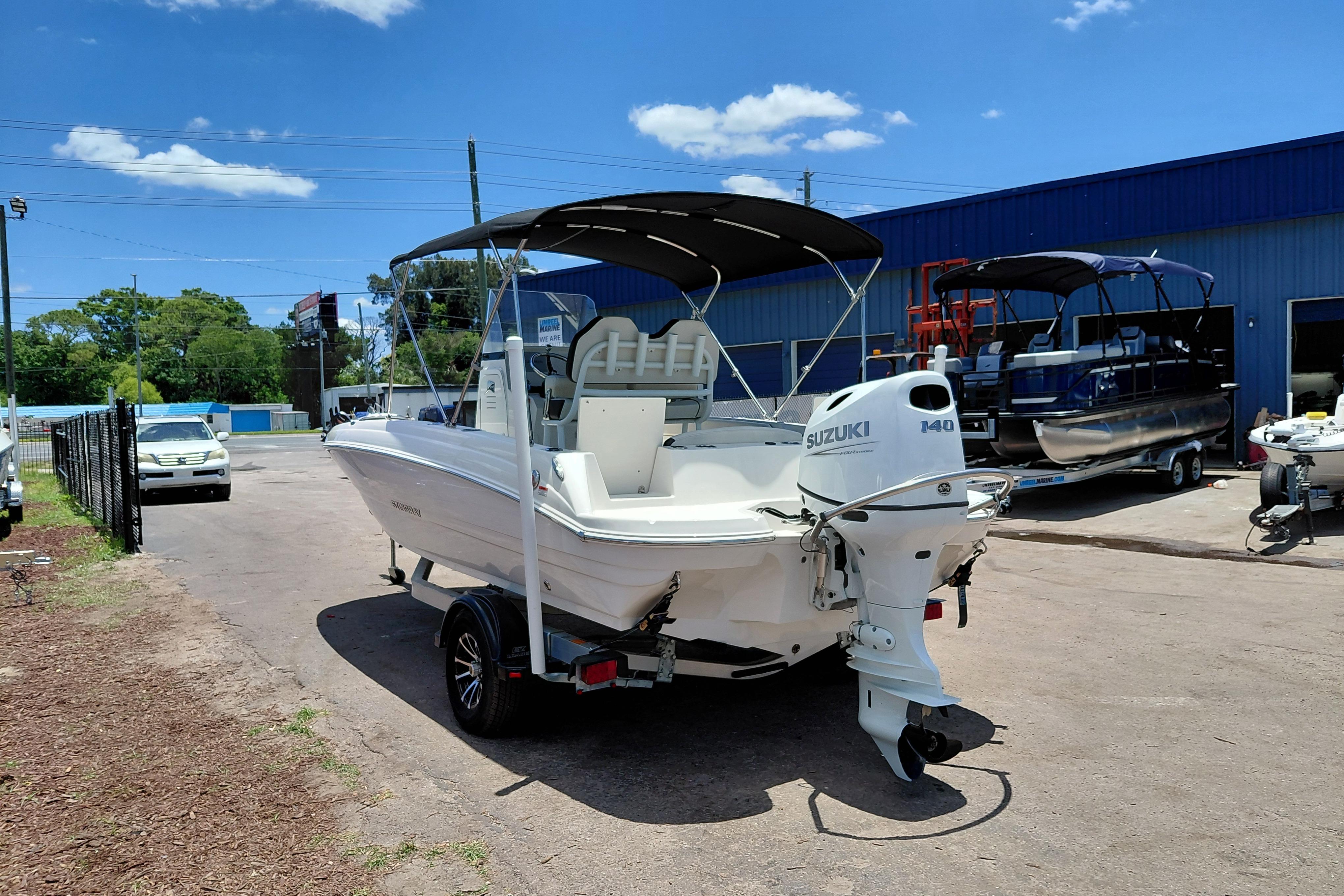 2023 Stingray 206 CC boat with Suzuki engine, parked outdoors under blue sky.