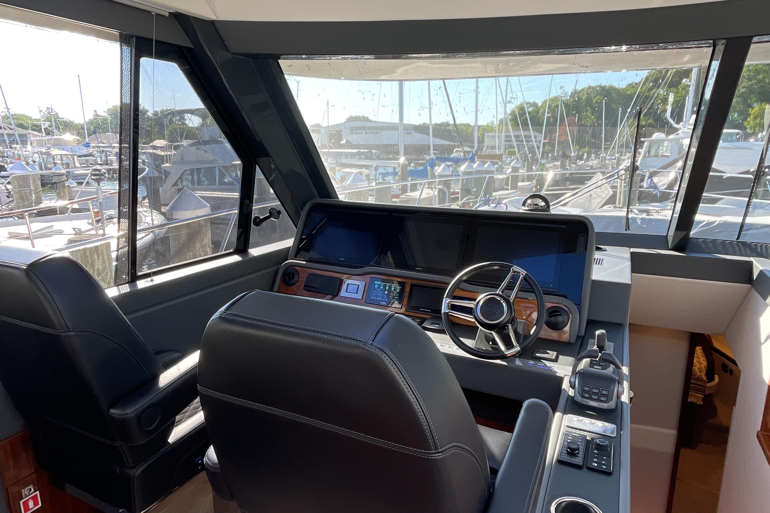 Interior view of 2025 Riviera 585 SUV yacht cockpit with steering wheel and navigation controls.