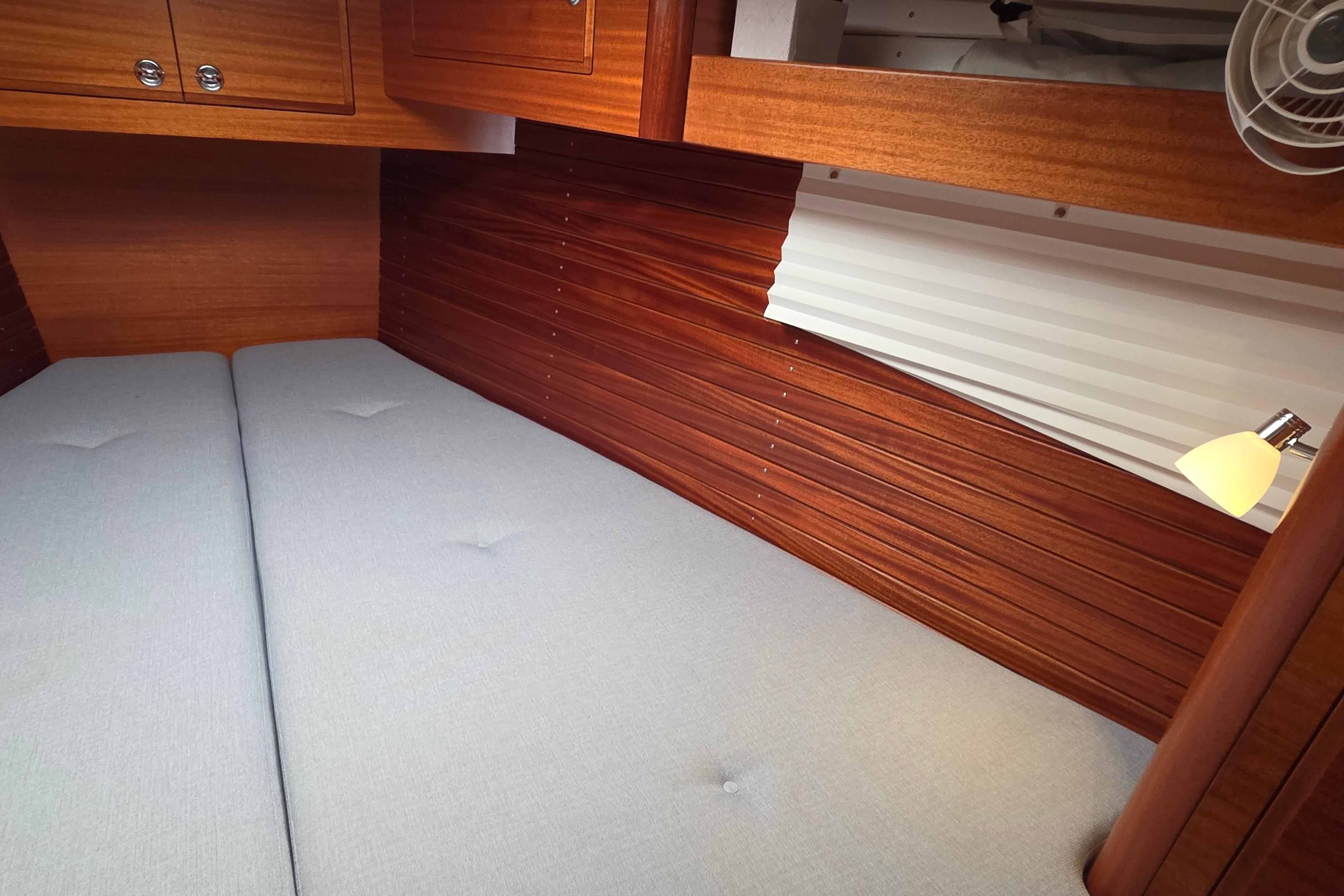 Cozy cabin interior of 2021 Hallberg-Rassy 40C yacht with wooden paneling and soft lighting.