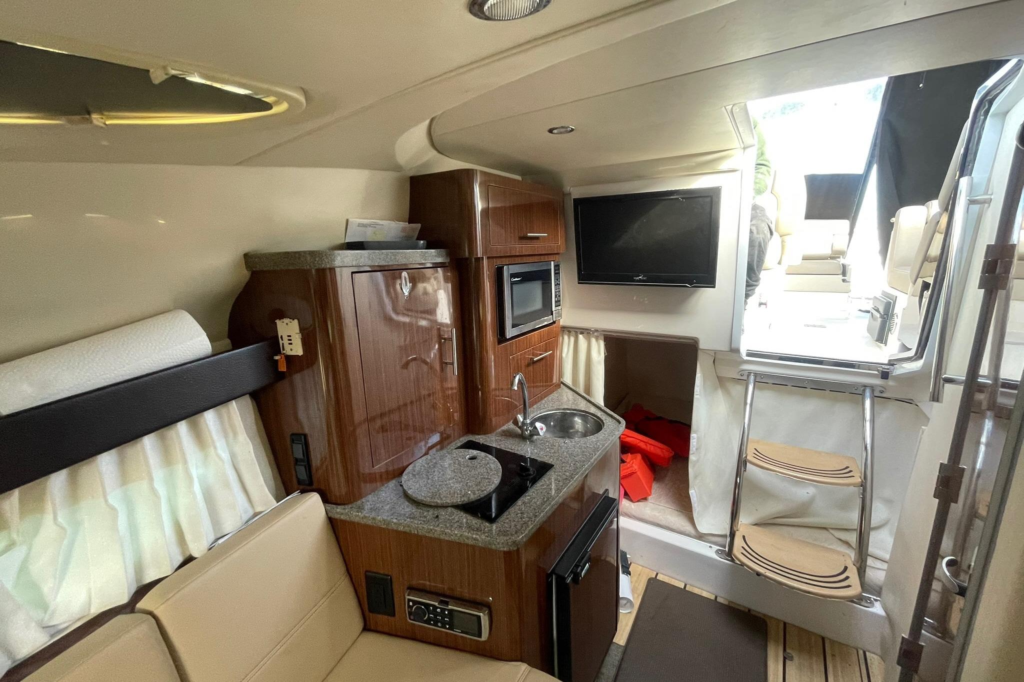 Interior of 2013 Regal 28 Express boat with kitchenette, seating, and TV.