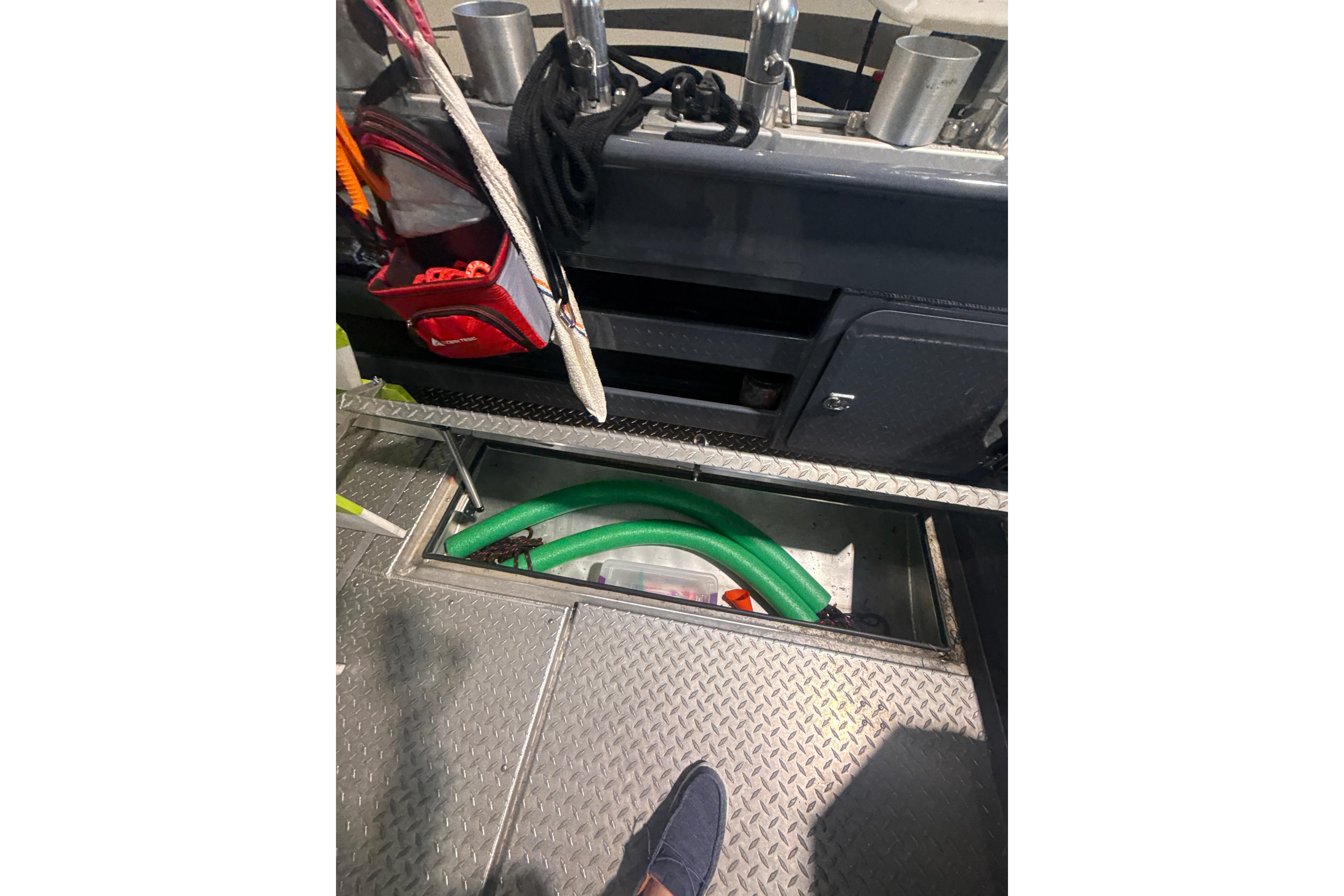 Interior view of 2022 Hewescraft 270 Alaskan Hardtop boat with storage compartment open.