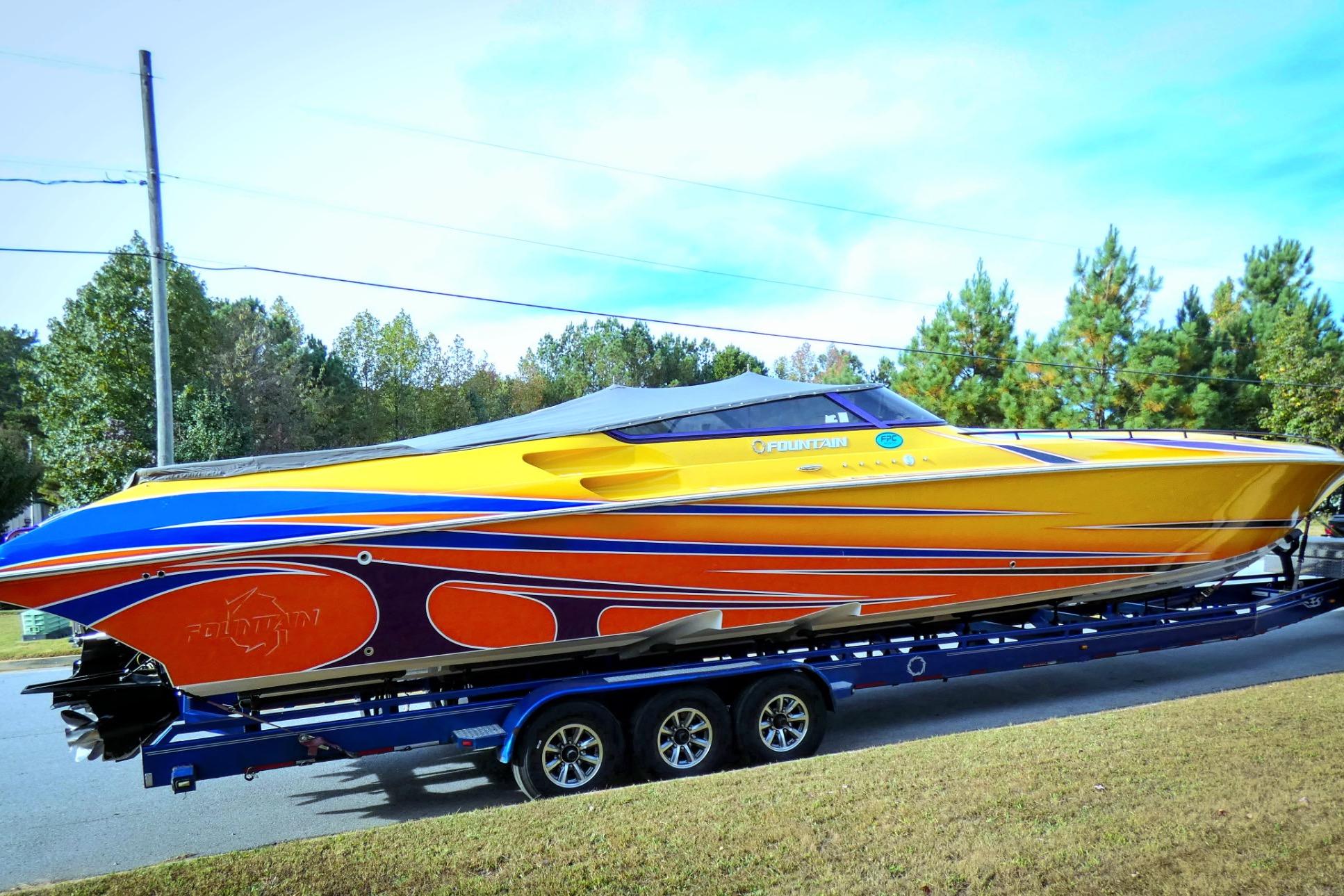 2006 Fountain 47 Lightning speedboat with vibrant yellow and orange design on a trailer.