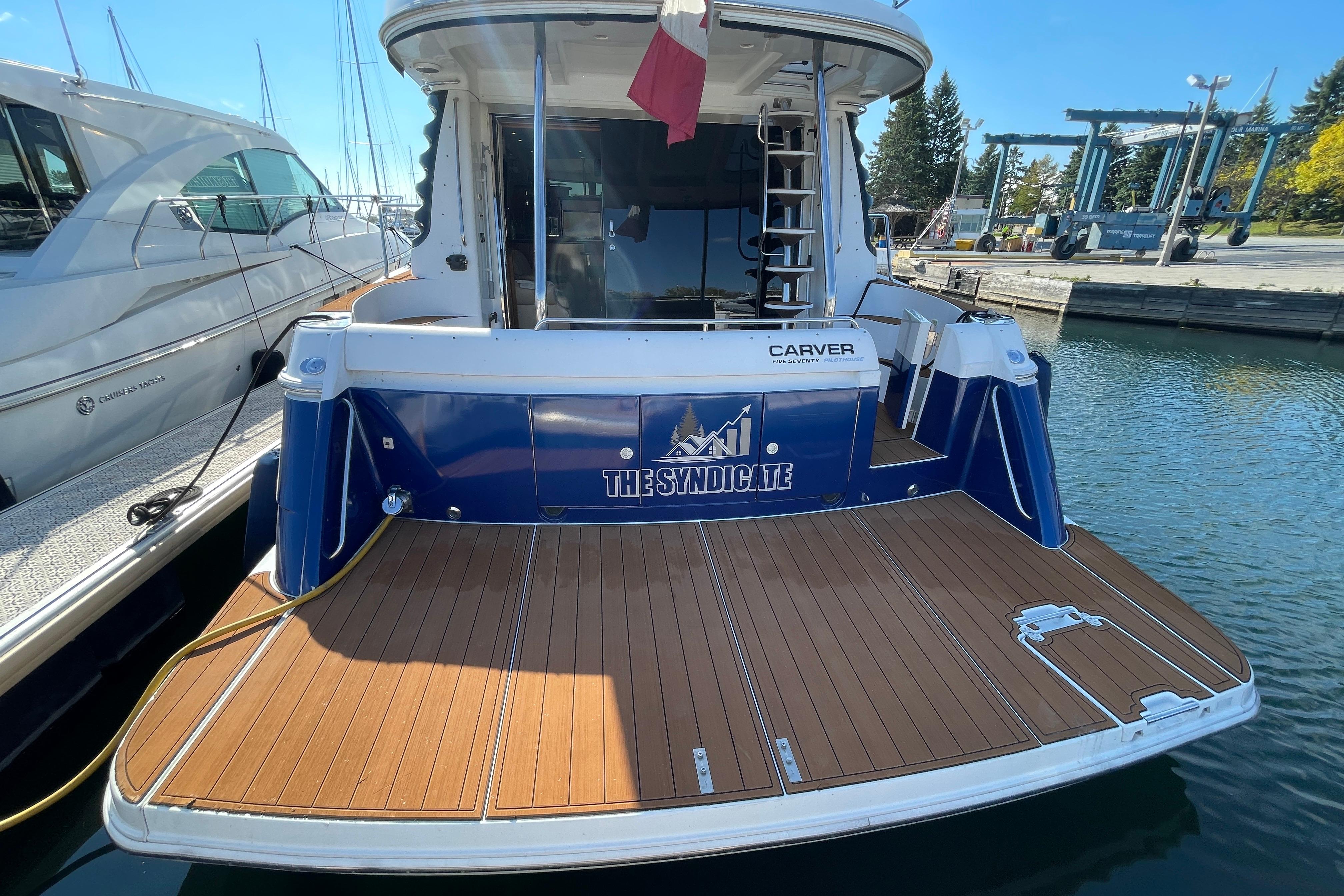 2002 Carver 570 Voyager Pilothouse yacht docked with wooden deck and blue hull.