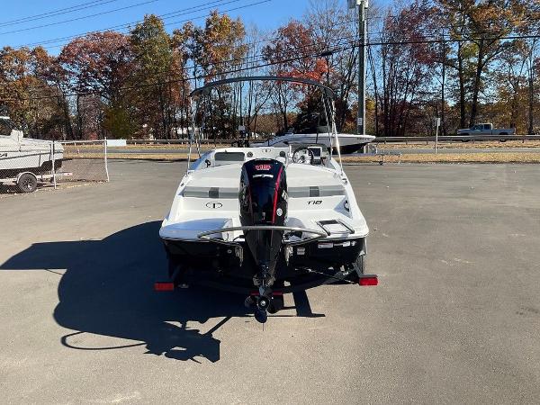 2025 Tahoe T18 boat with outboard motor, parked on pavement, surrounded by autumn trees.