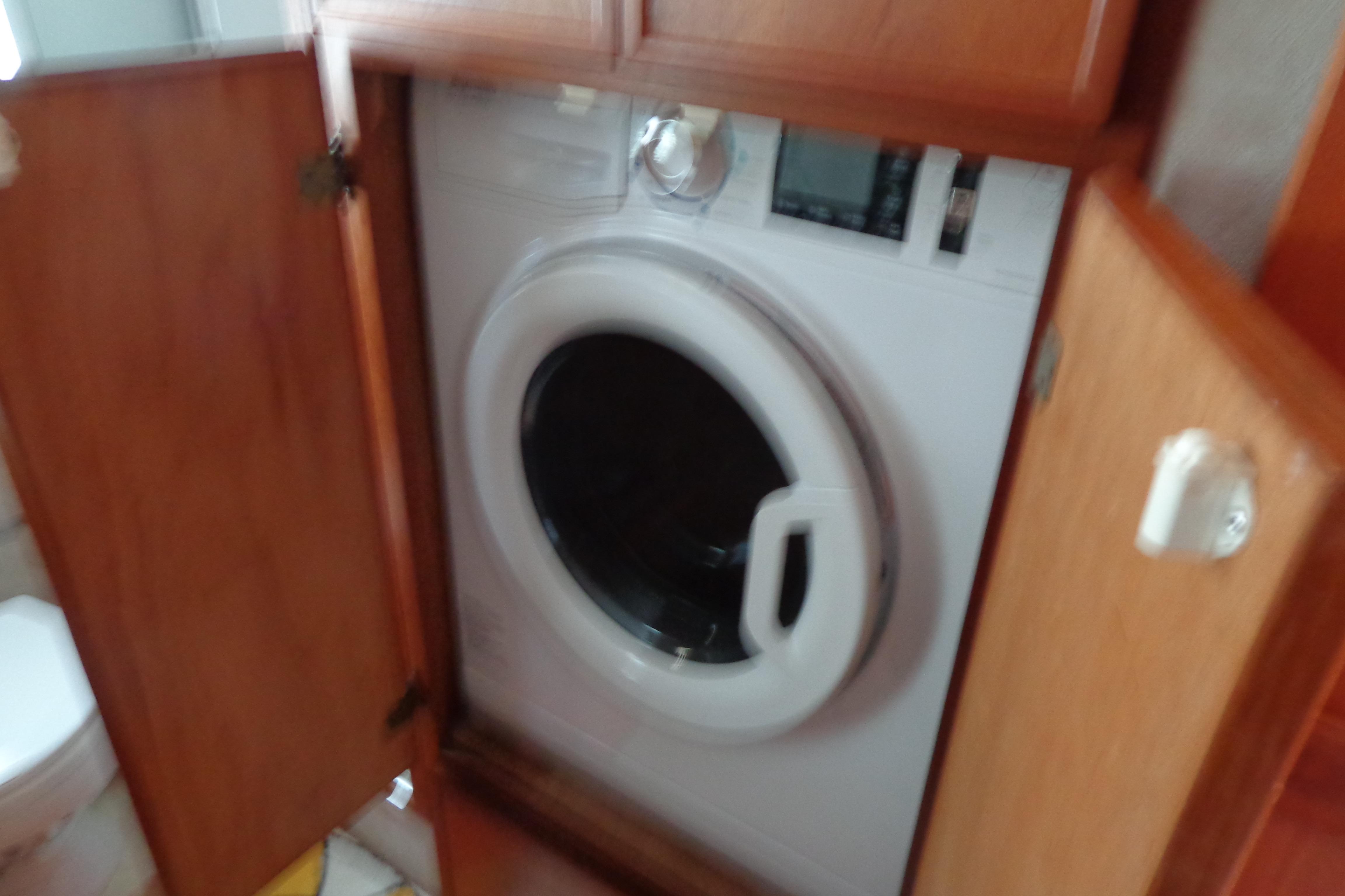 Washing machine inside a 1992 Cruise-A-Home Corsair 4200, with wooden cabinet doors open.