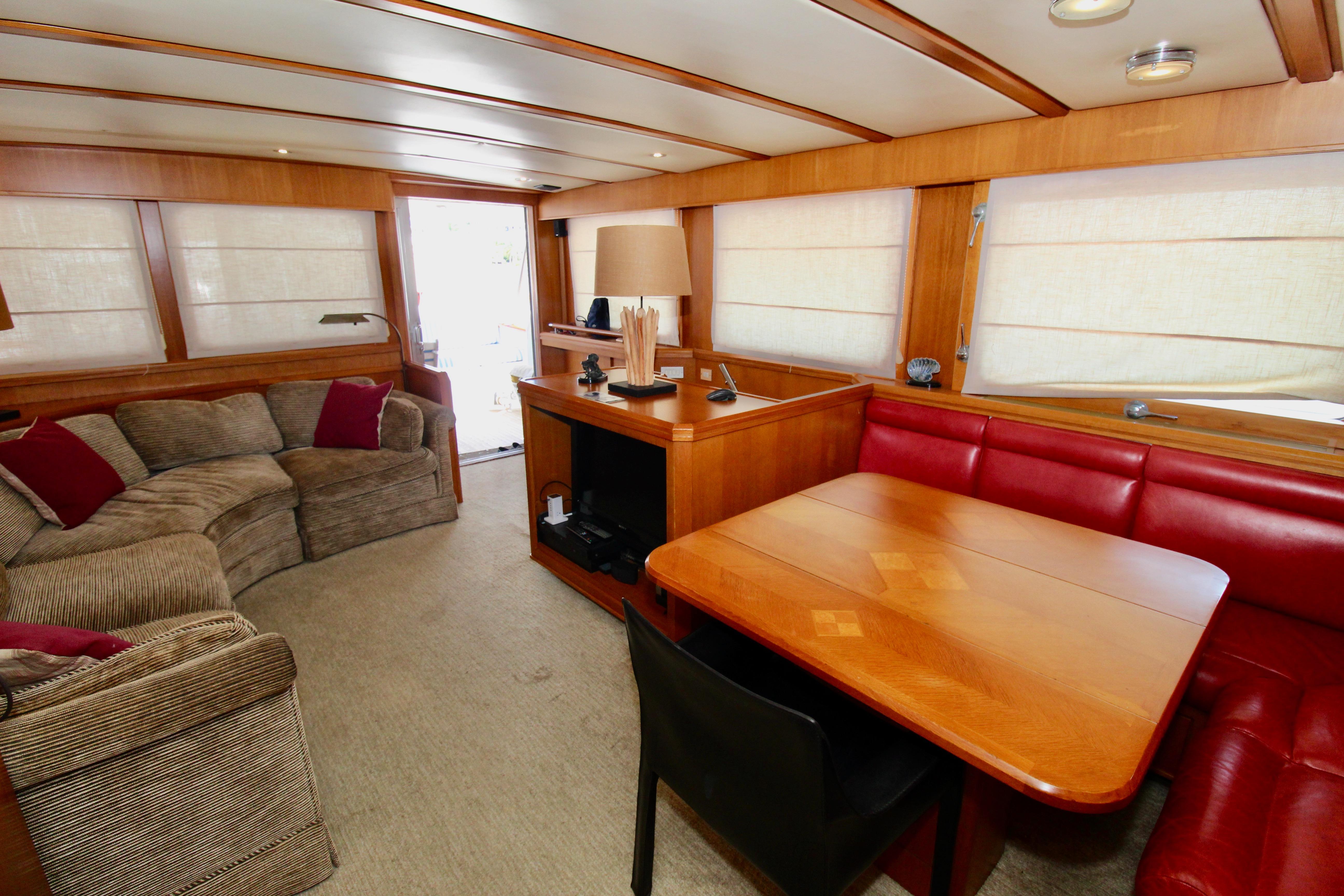 Luxurious 1990 Hakvoort Motor Yacht interior with cozy seating and elegant wooden dining area.