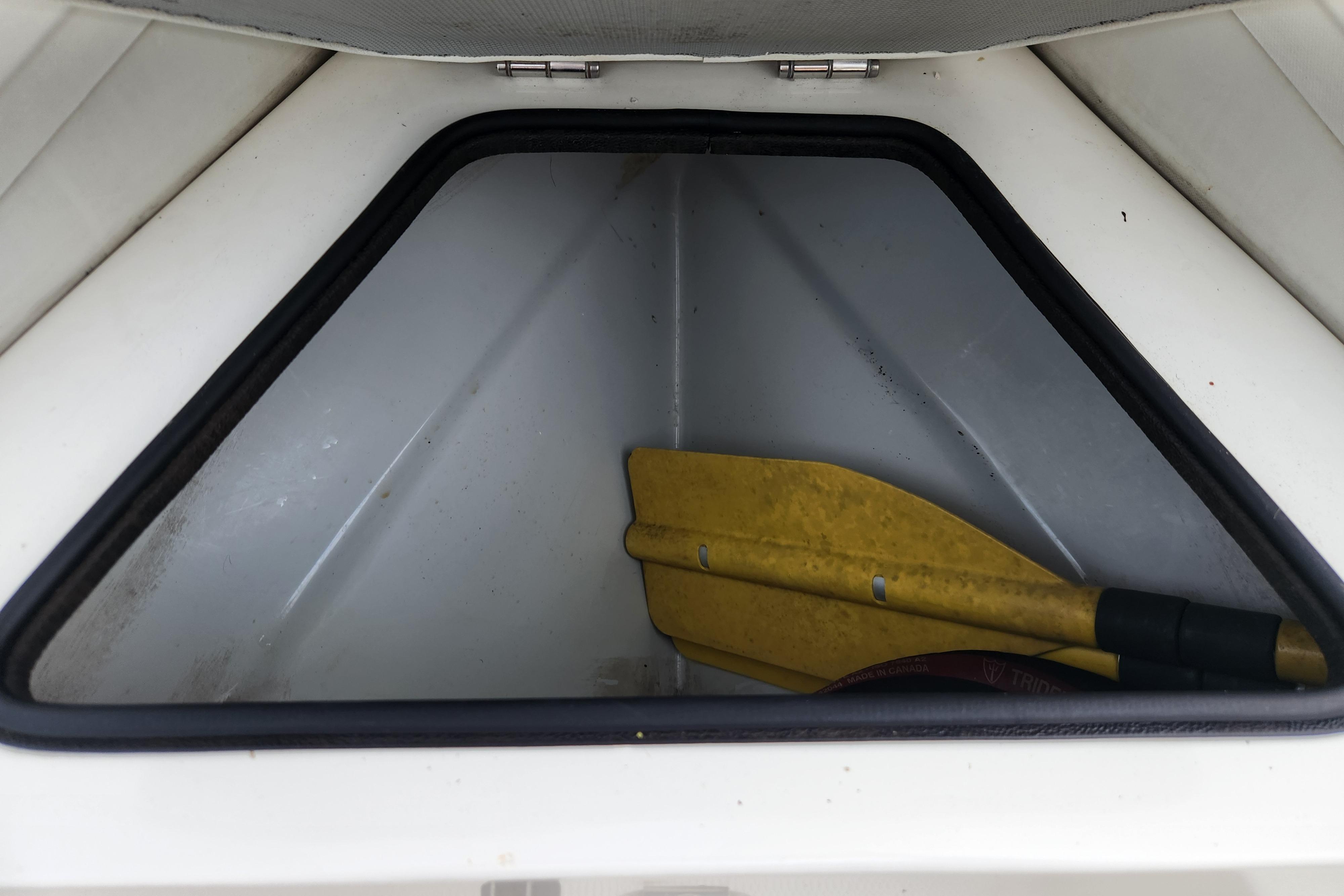 Storage compartment of 2019 Novurania DL 400 boat with yellow paddle inside.