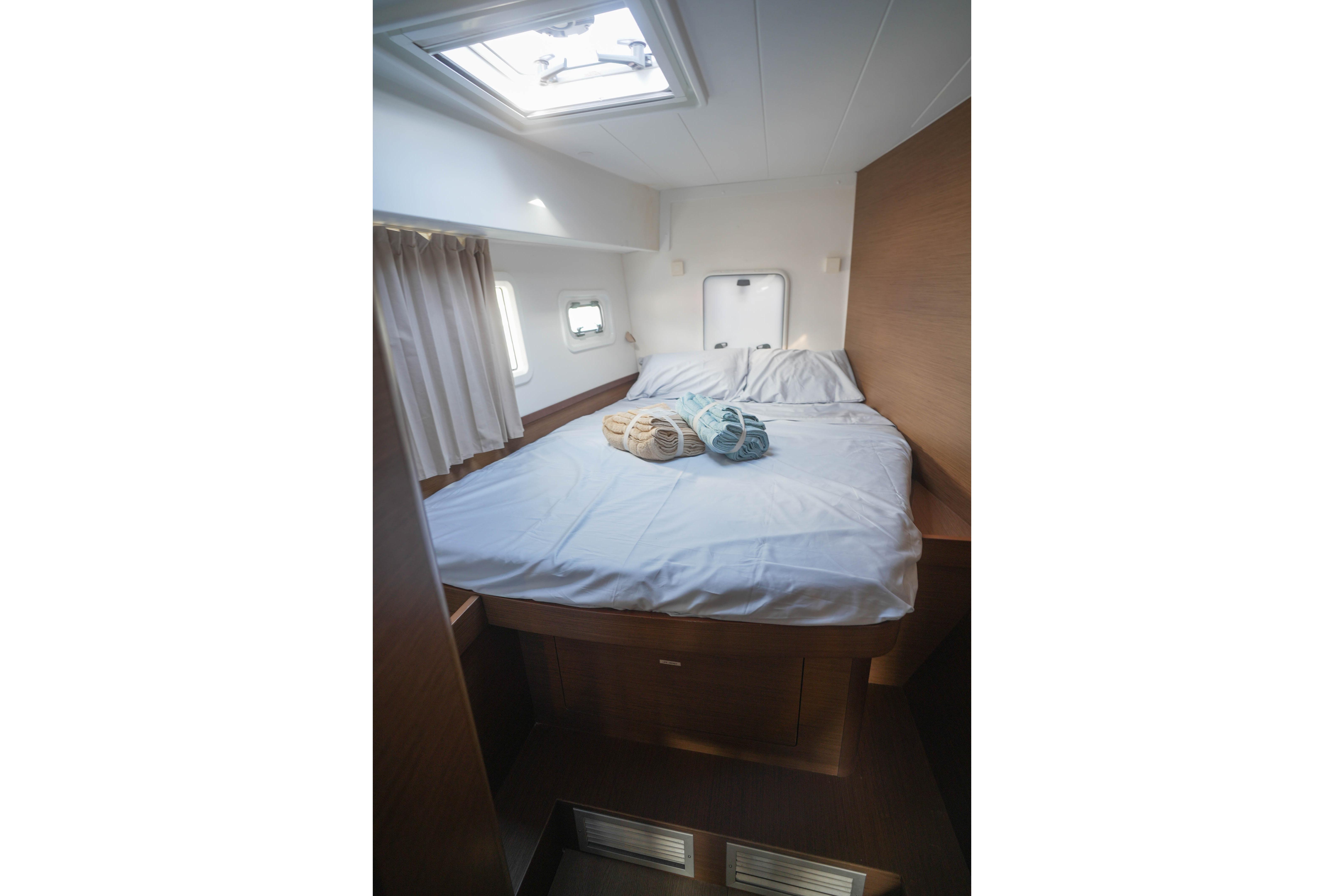 Cozy bedroom interior of 2019 Lagoon 42 catamaran with skylight and neatly arranged bed.