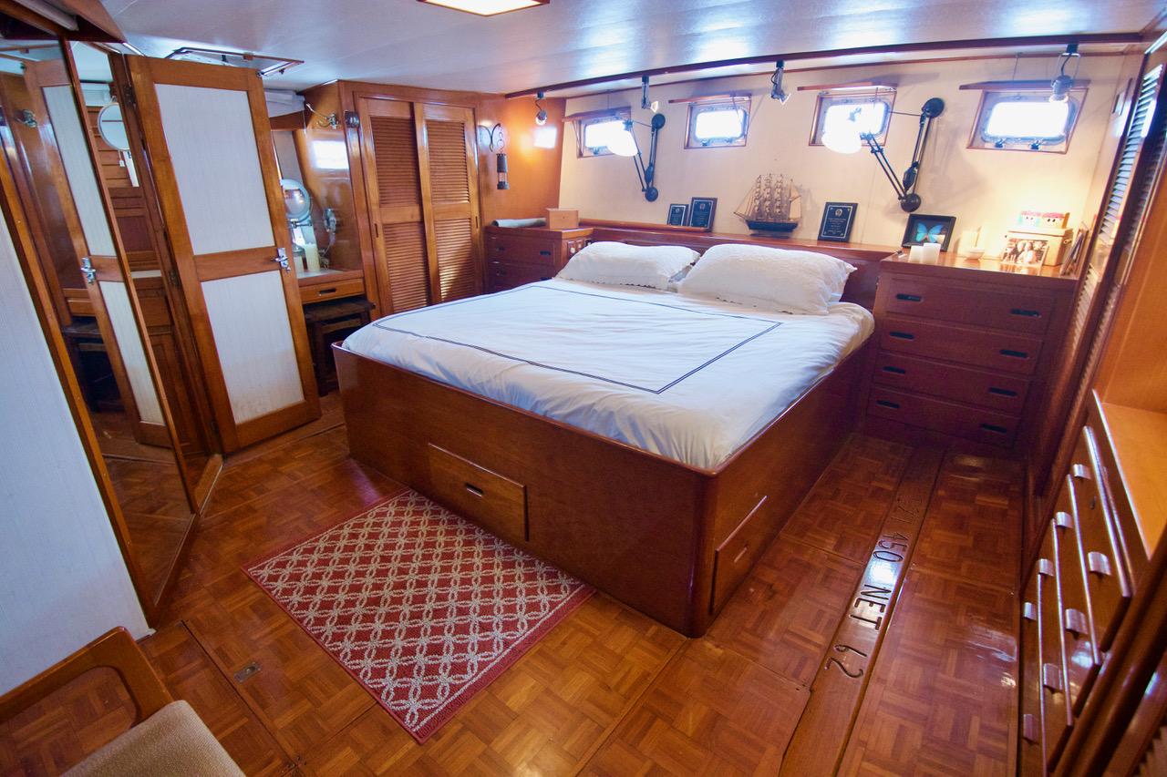 Luxurious 1969 Grand Banks Classic yacht bedroom with wooden interior and cozy bed.