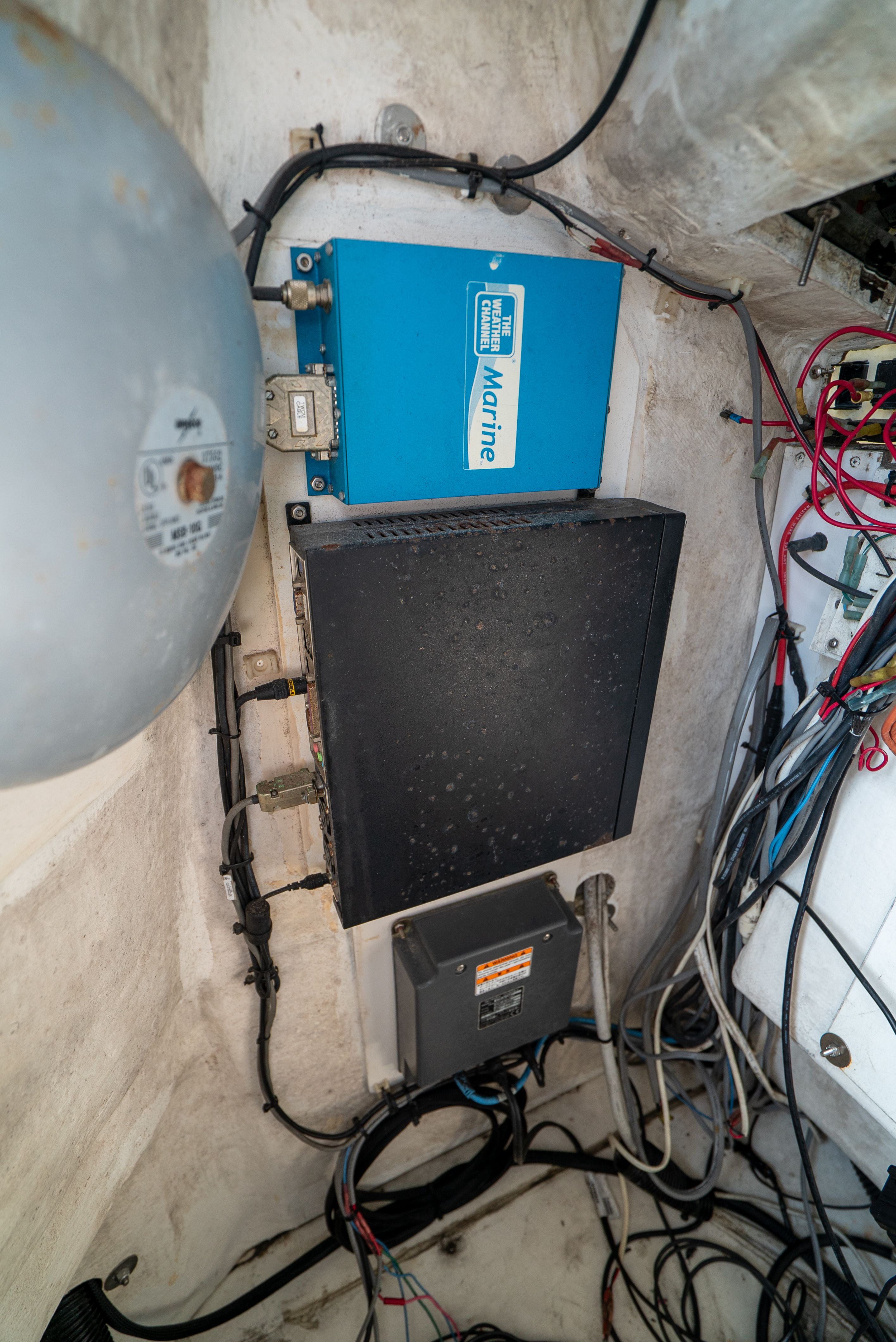 Electronics and wiring in a boat's engine room, featuring a blue marine device.