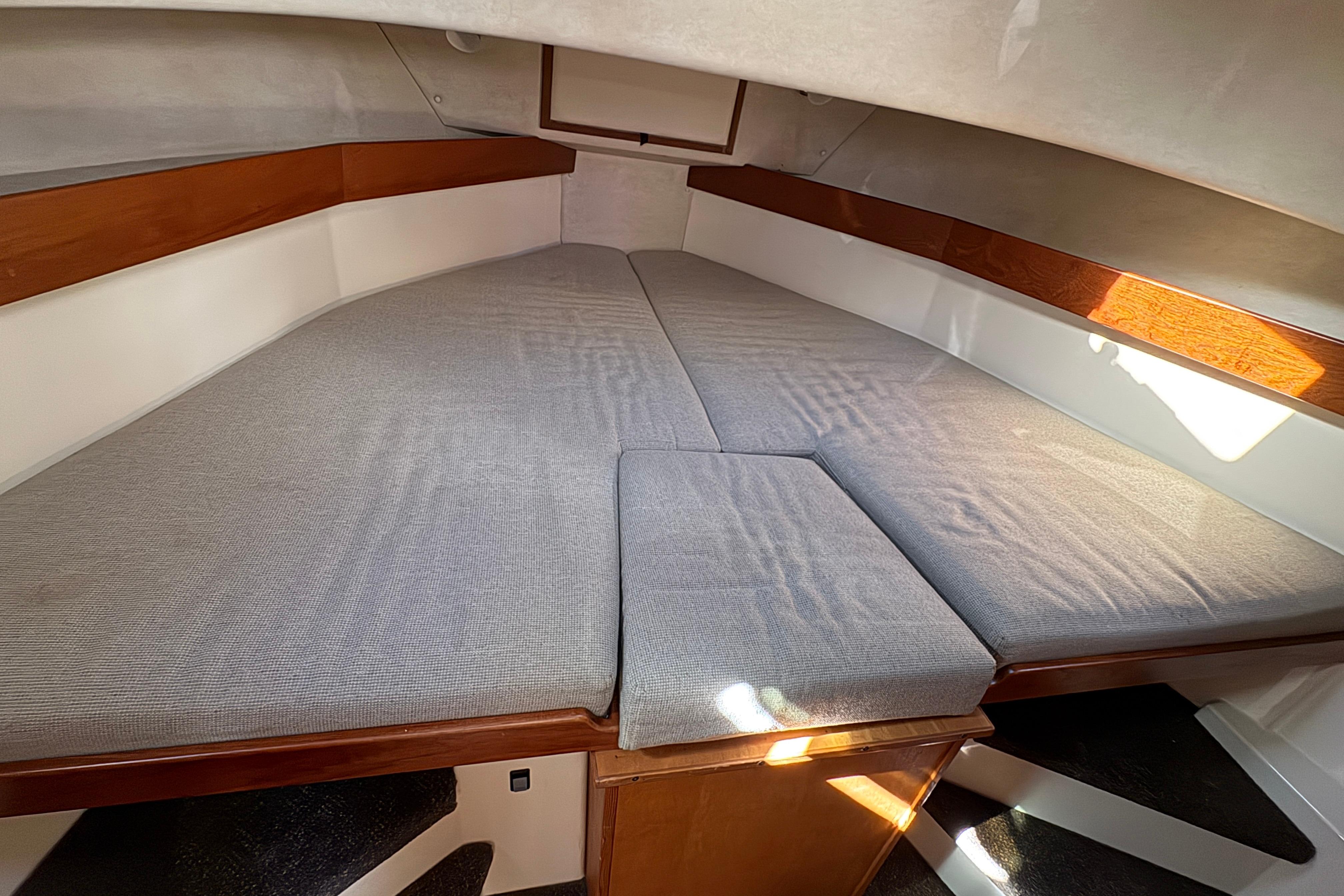 Cozy cabin interior of 2004 Nordic Tug 32 with cushioned sleeping area.