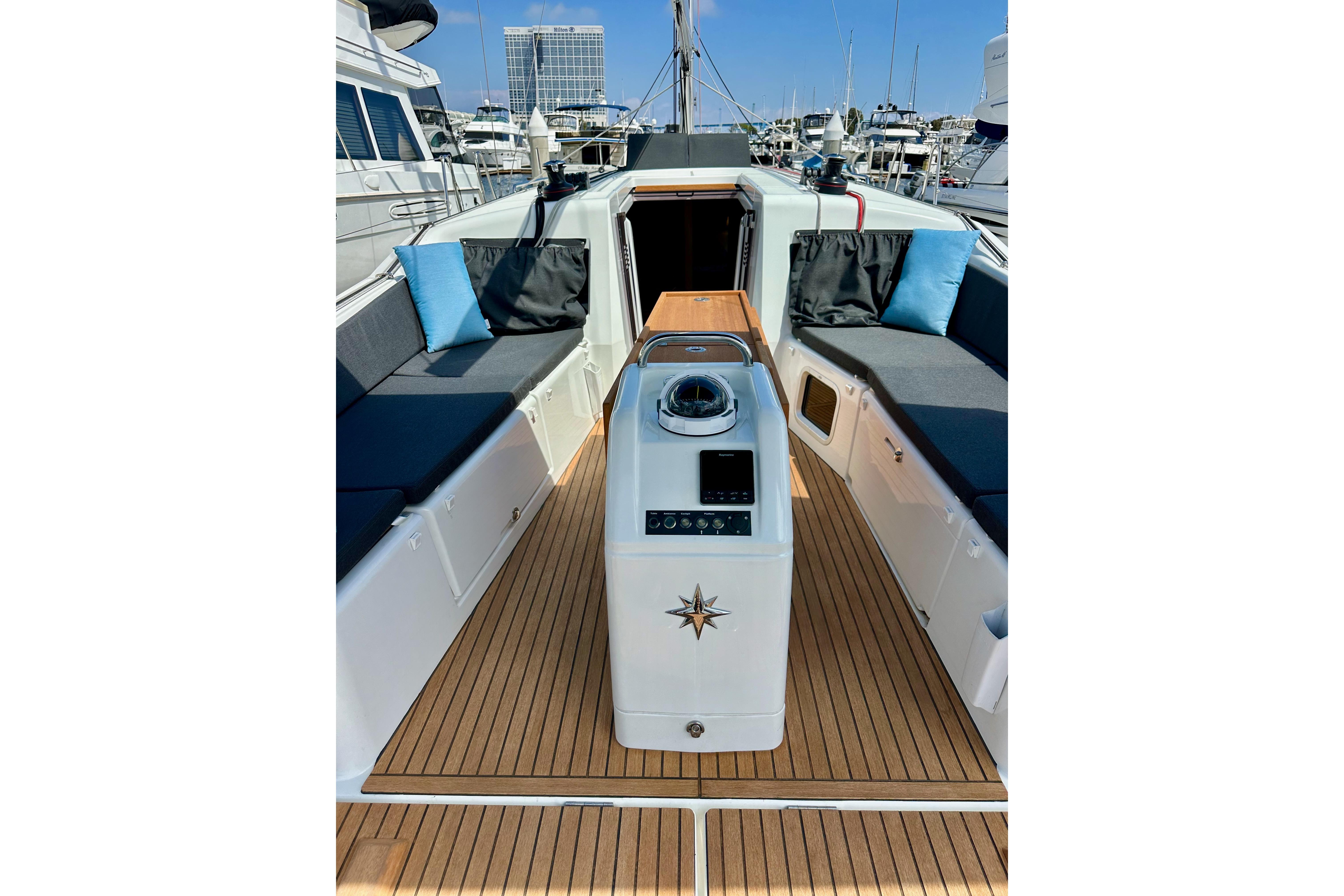 2024 Jeanneau Sun Odyssey 410 yacht cockpit with teak flooring and cushioned seating.