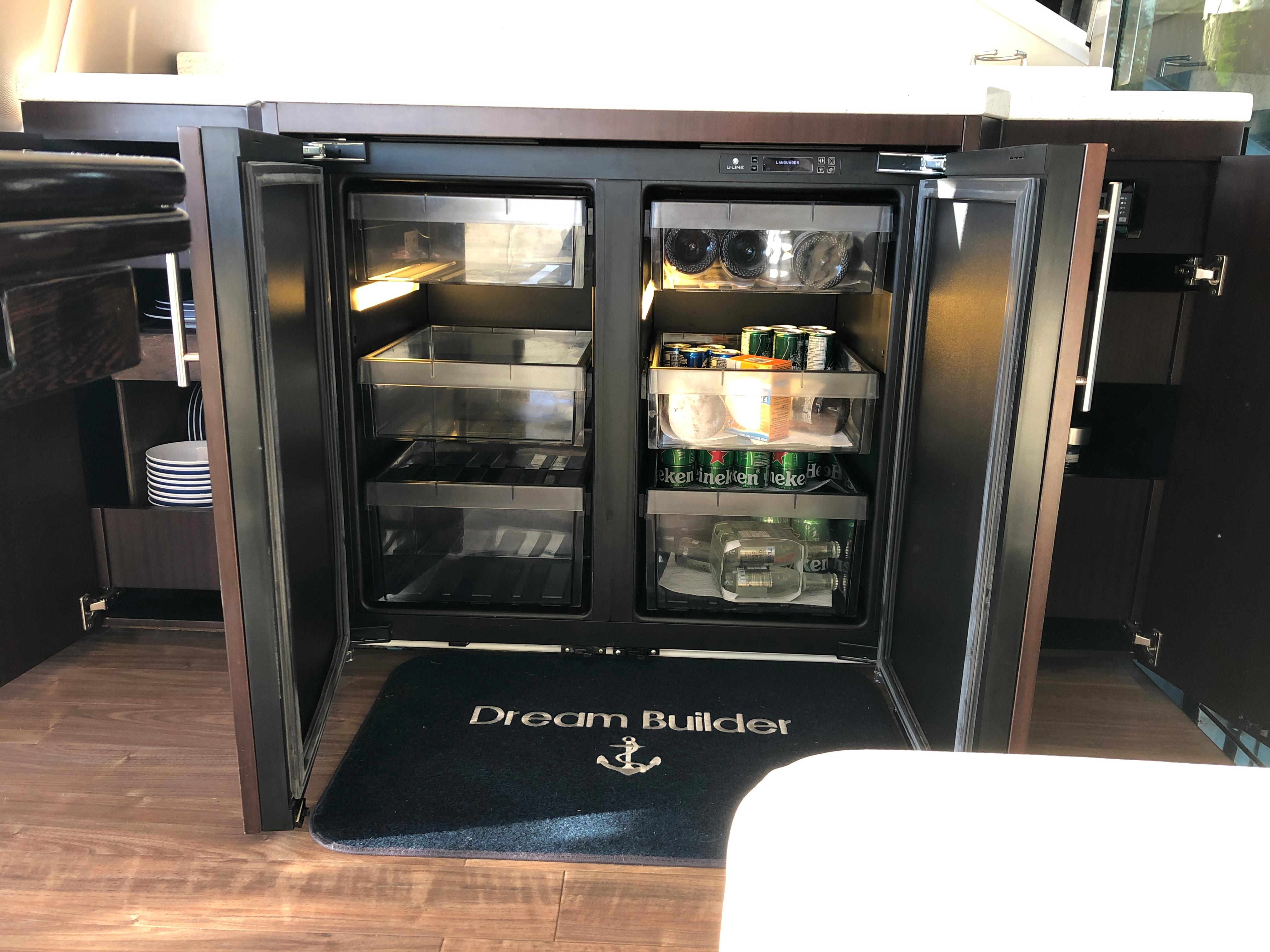 Open mini fridge on 2017 Regal 53 Sport Coupe yacht, stocked with drinks and snacks.