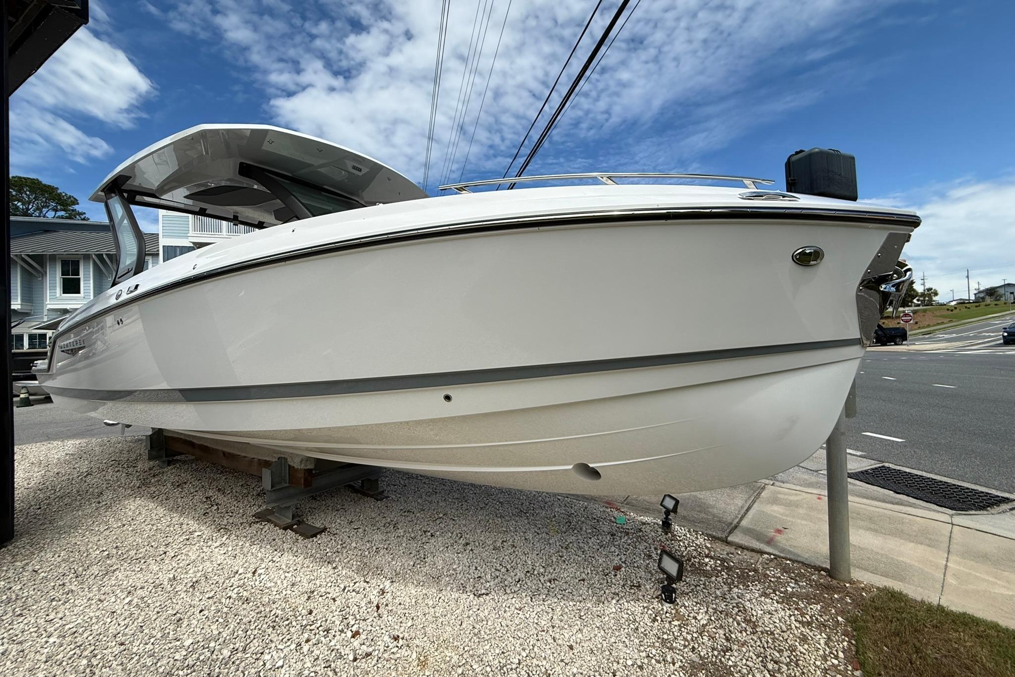 2027 Monterey Elite 30 OB boat displayed outdoors on gravel, under a partly cloudy sky.