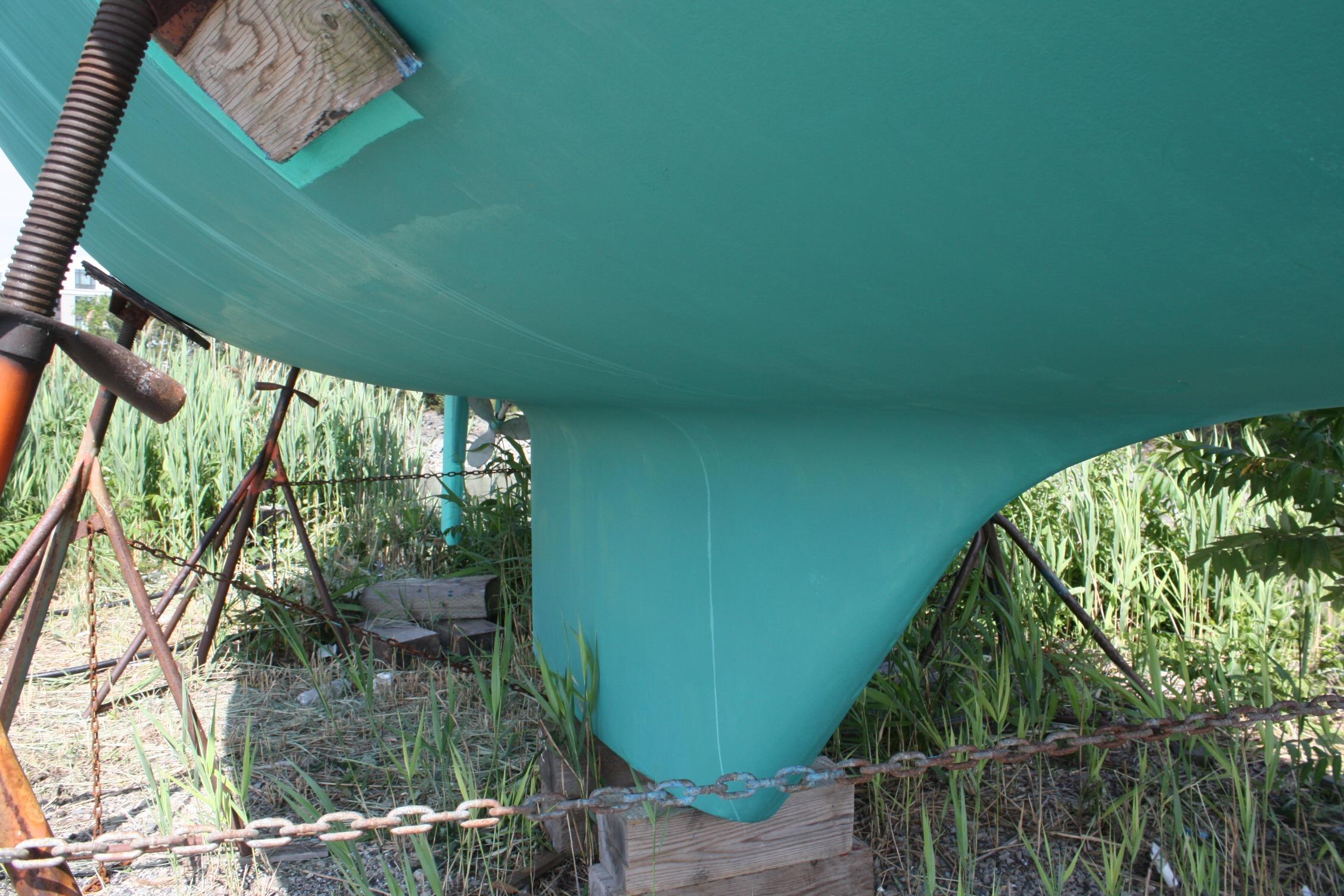 Bottom view of a 1981 S2 9.2A sailboat hull on stands, surrounded by grass.