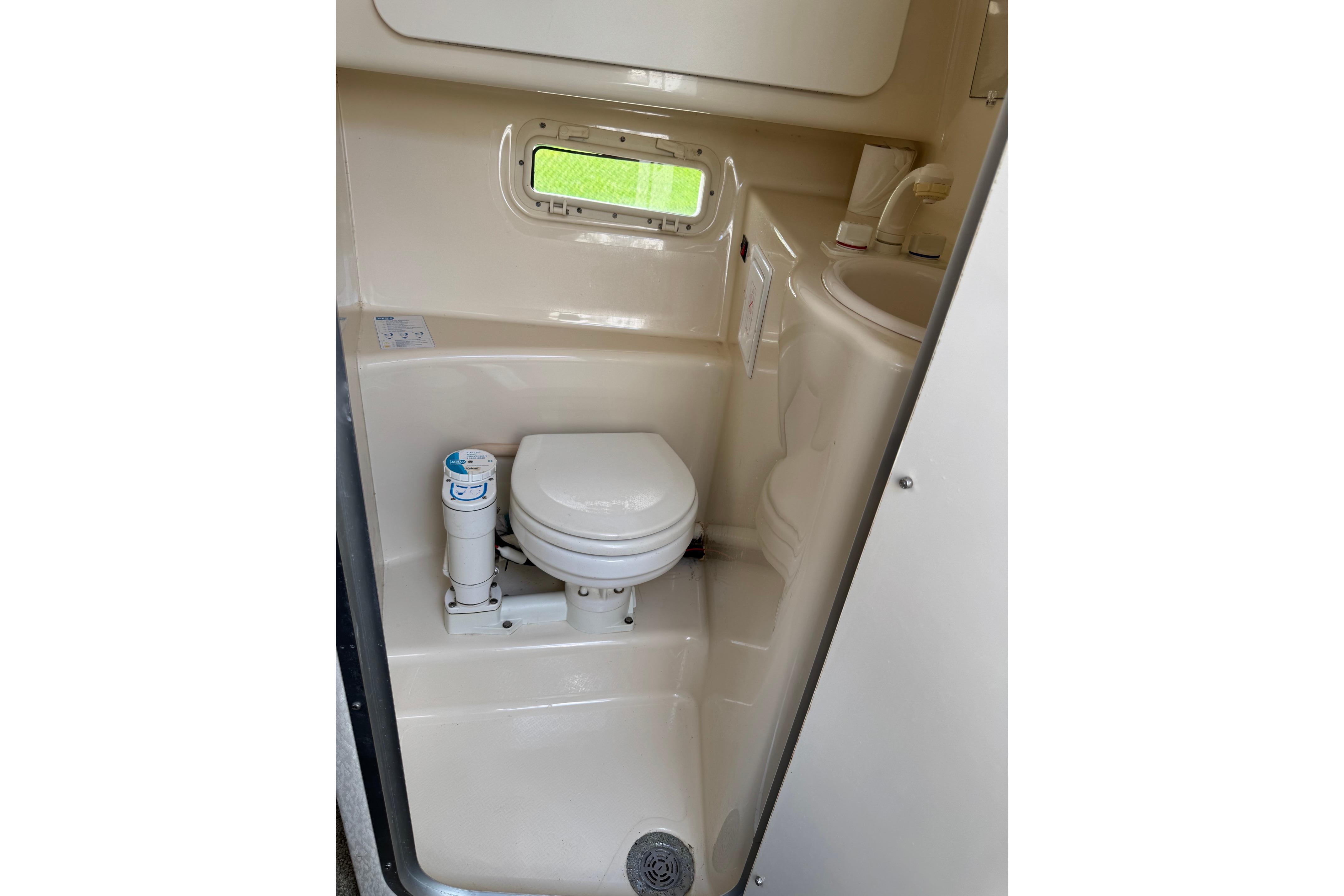 Compact bathroom in a 2000 Maxum 2400 SCR boat, featuring a toilet and sink.