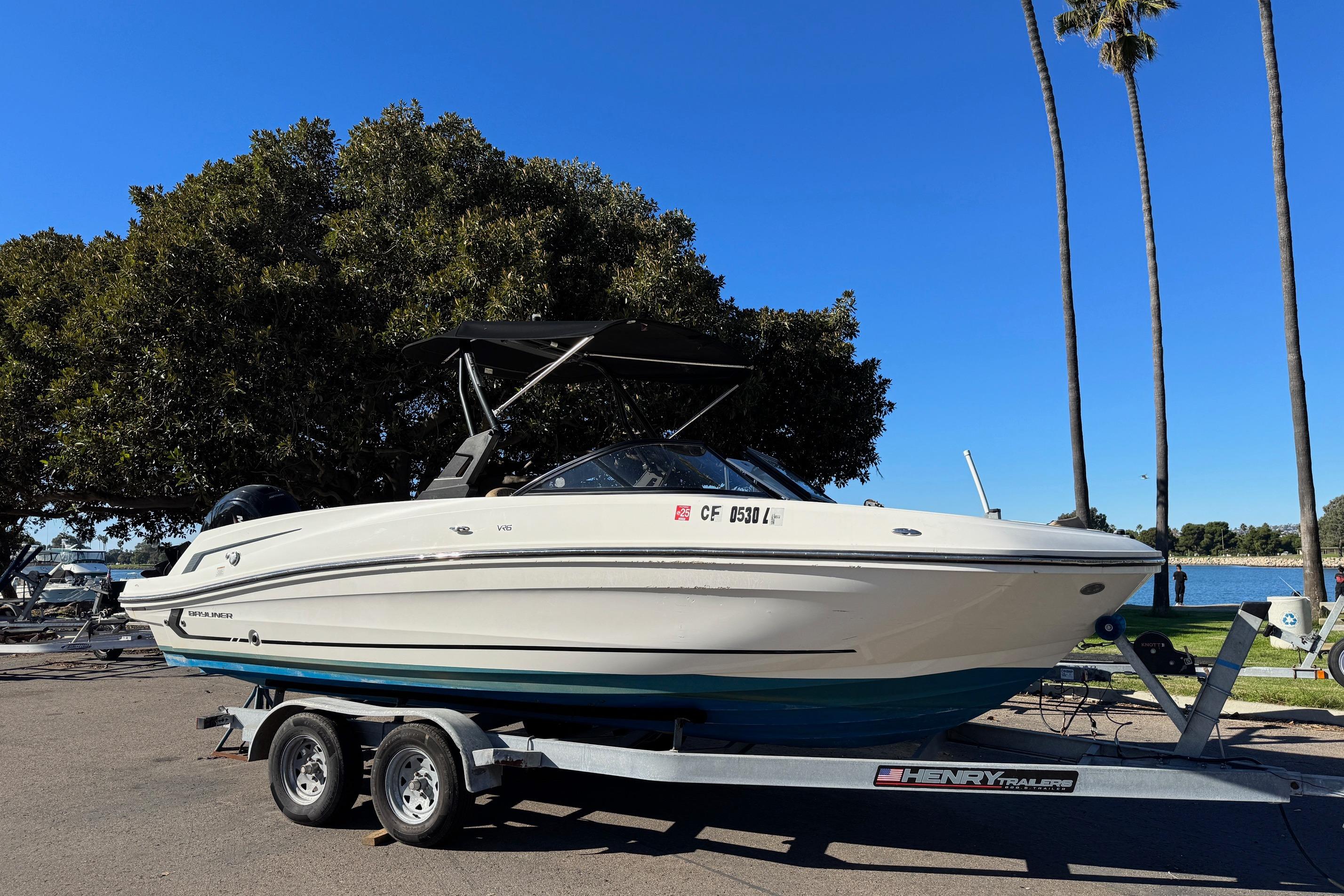 2022 Bayliner VR6 Bowrider OB on trailer, parked near a lake with palm trees.
