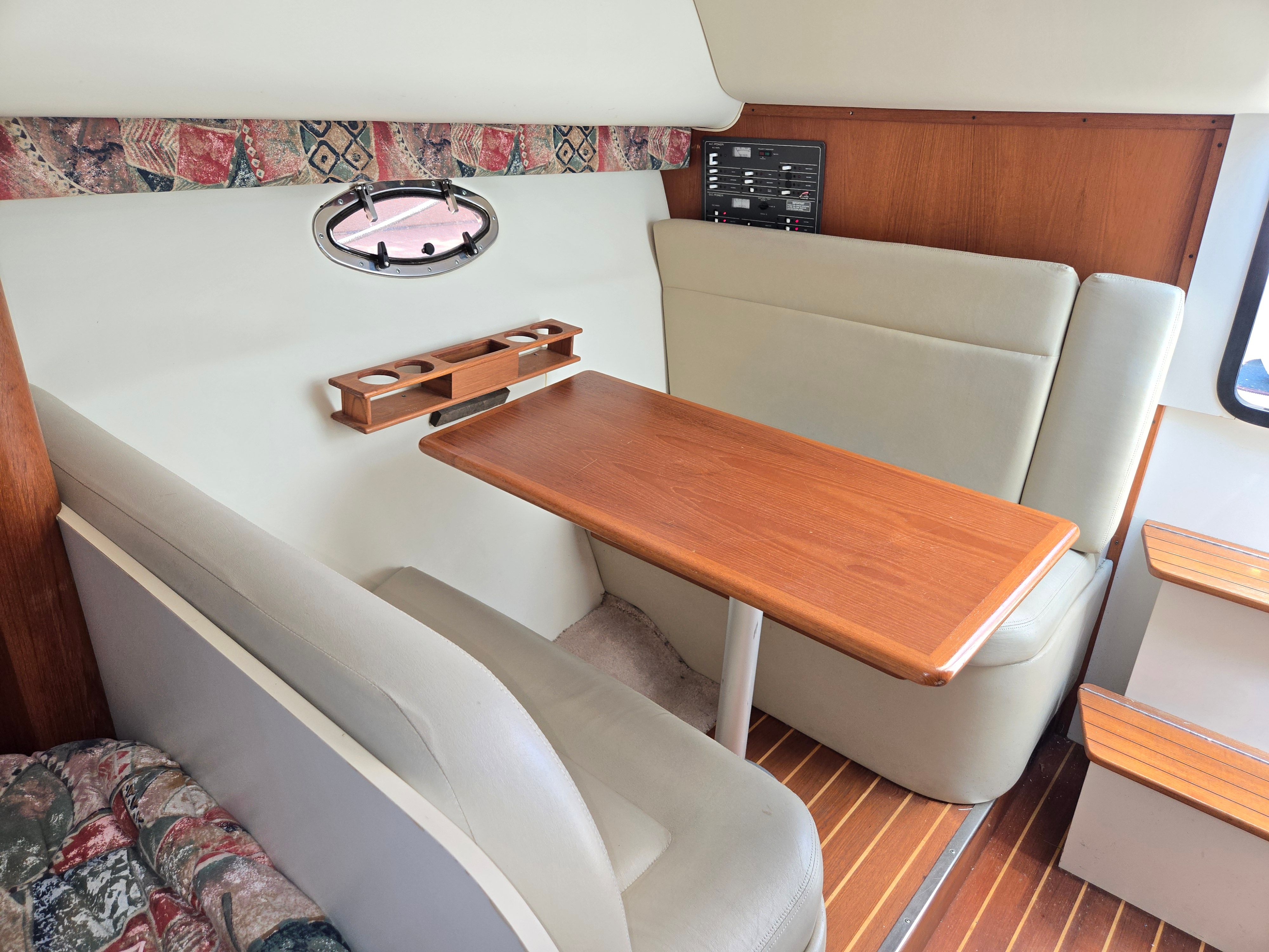 Interior of a 1997 Tiara Yachts Open with a wooden table and cushioned seating.