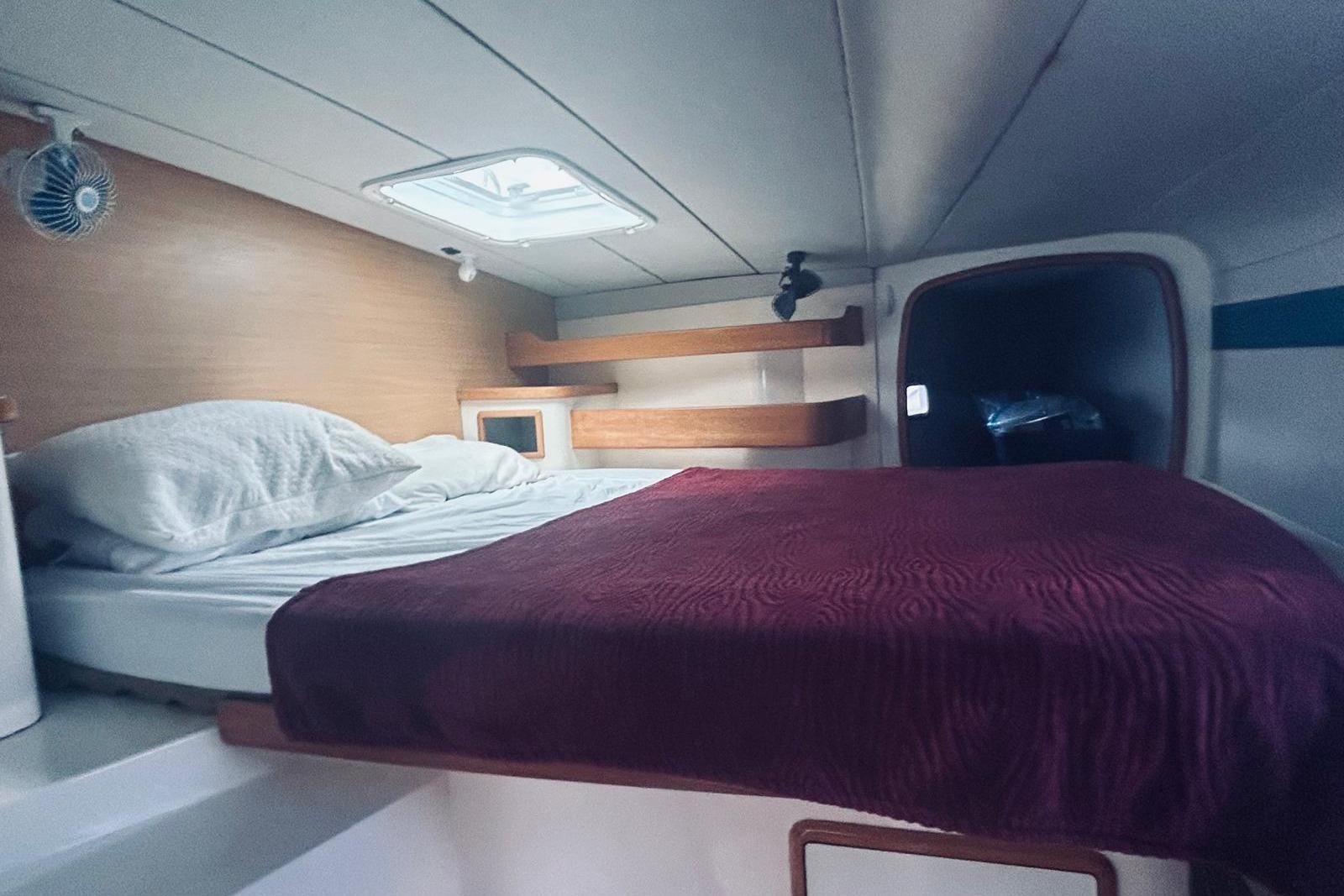 Cozy cabin interior of a 2001 Robertson & Caine Leopard yacht with a bed and porthole.