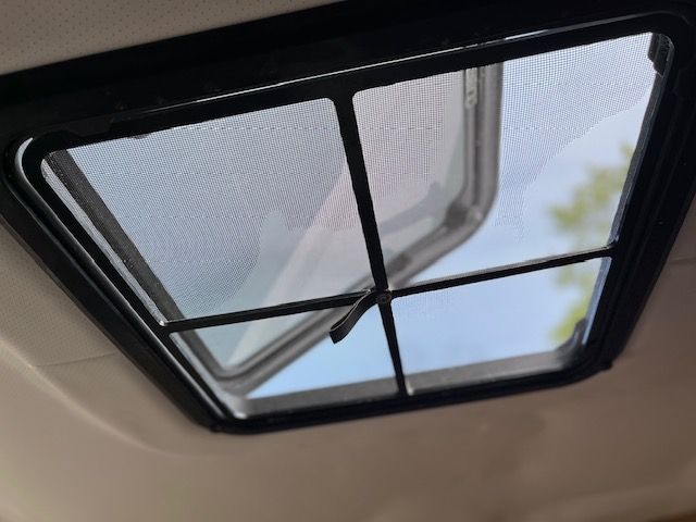 An open skylight with a grid, showing the blue sky.