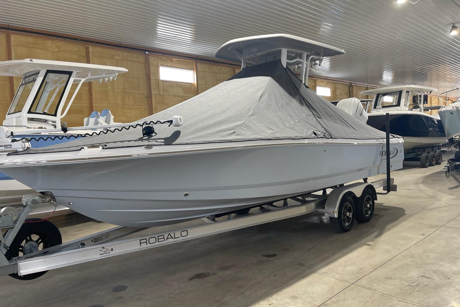 2024 Robalo 246 Cayman boat covered on trailer in indoor storage facility.