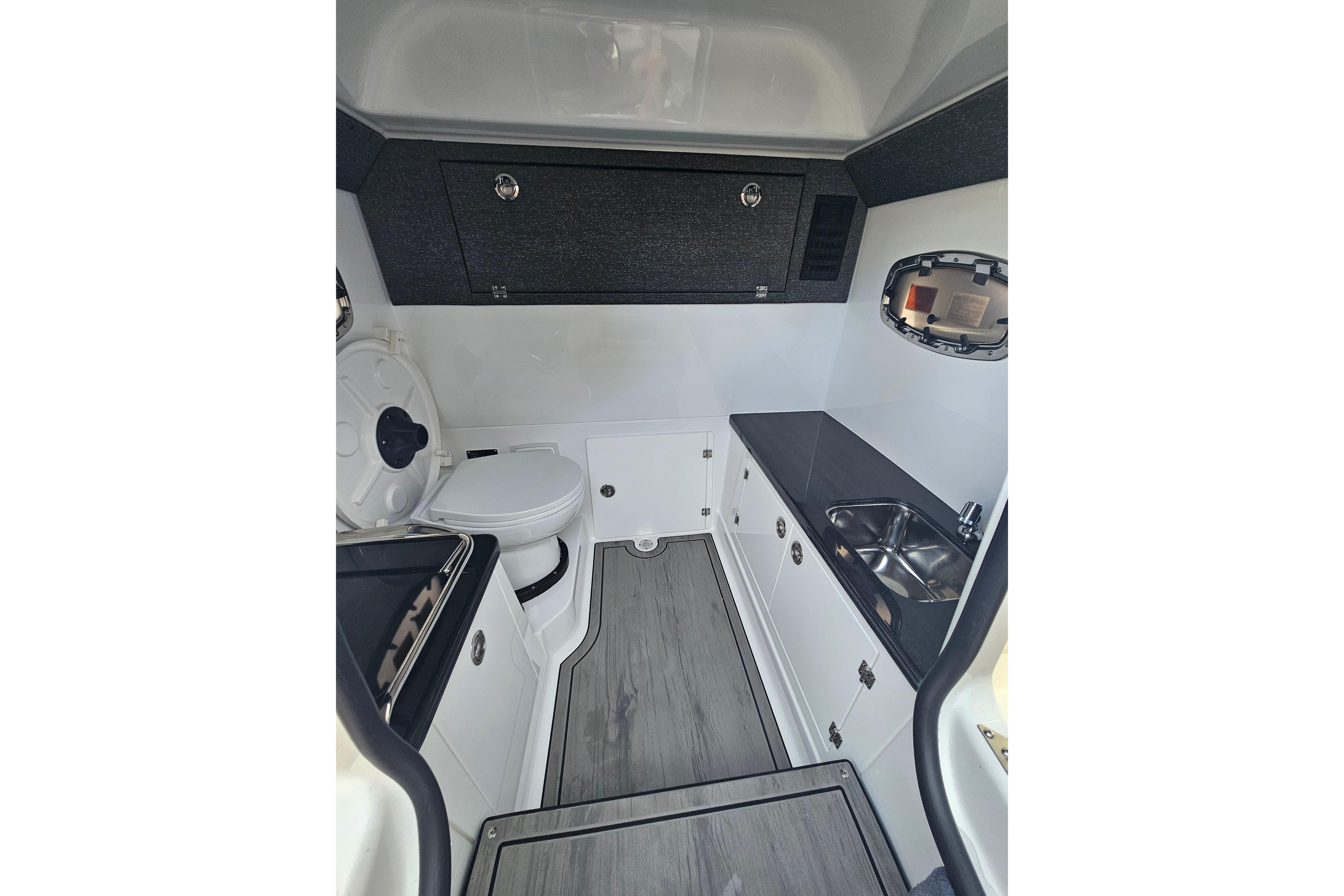 Interior of 2026 Monterey Elite 27 OB boat featuring compact kitchenette and toilet.