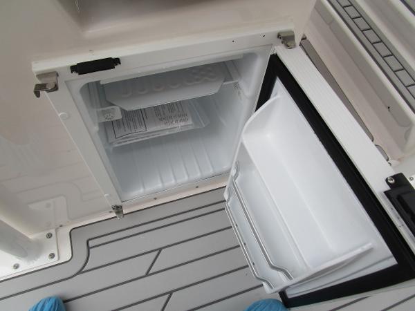 Open mini fridge on Solara S-250 CW boat, 2025 model, with gray deck flooring.