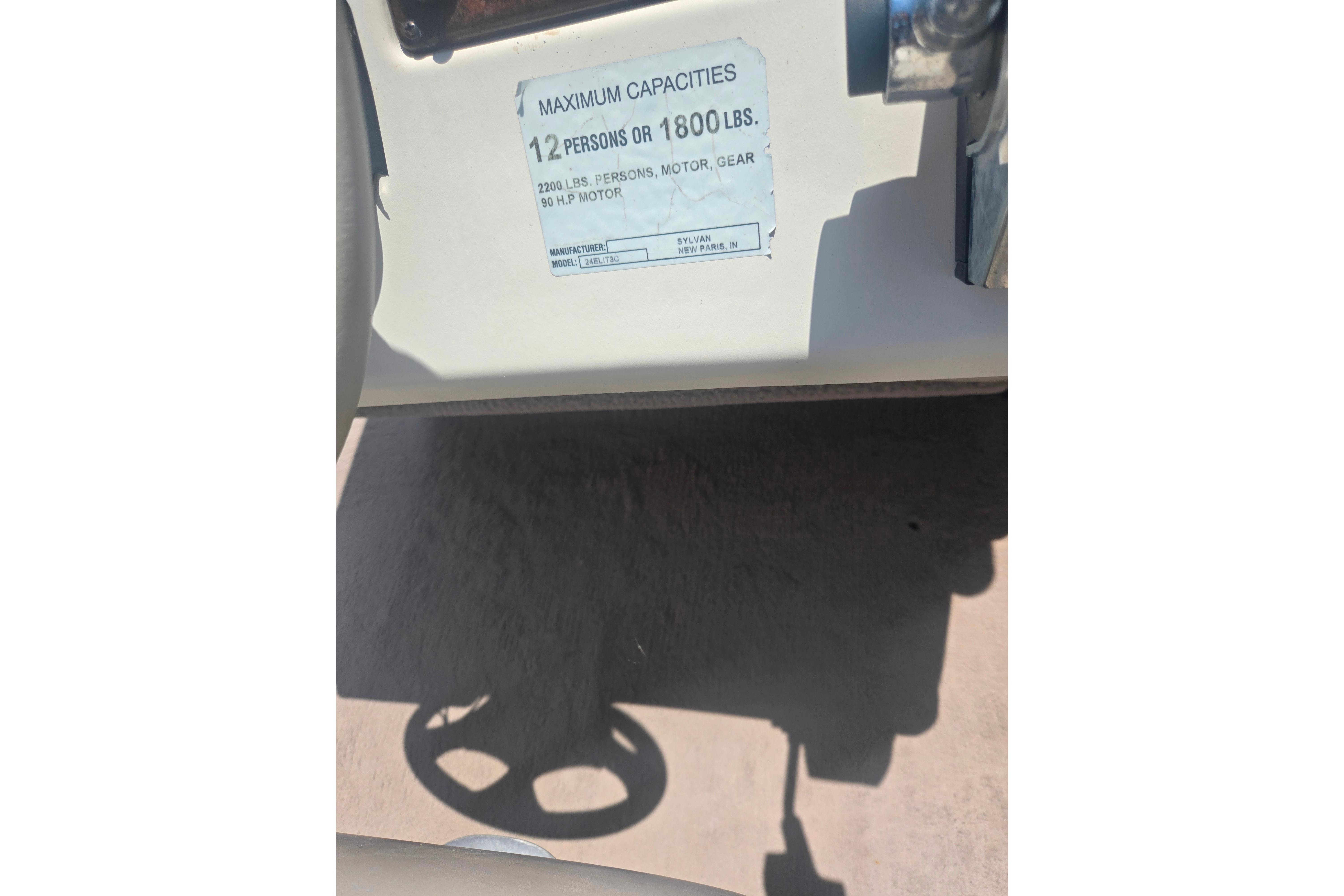 Capacity label on 2000 Sylvan 824 Elite Cruise boat, showing 12-person or 1800 lbs limit.