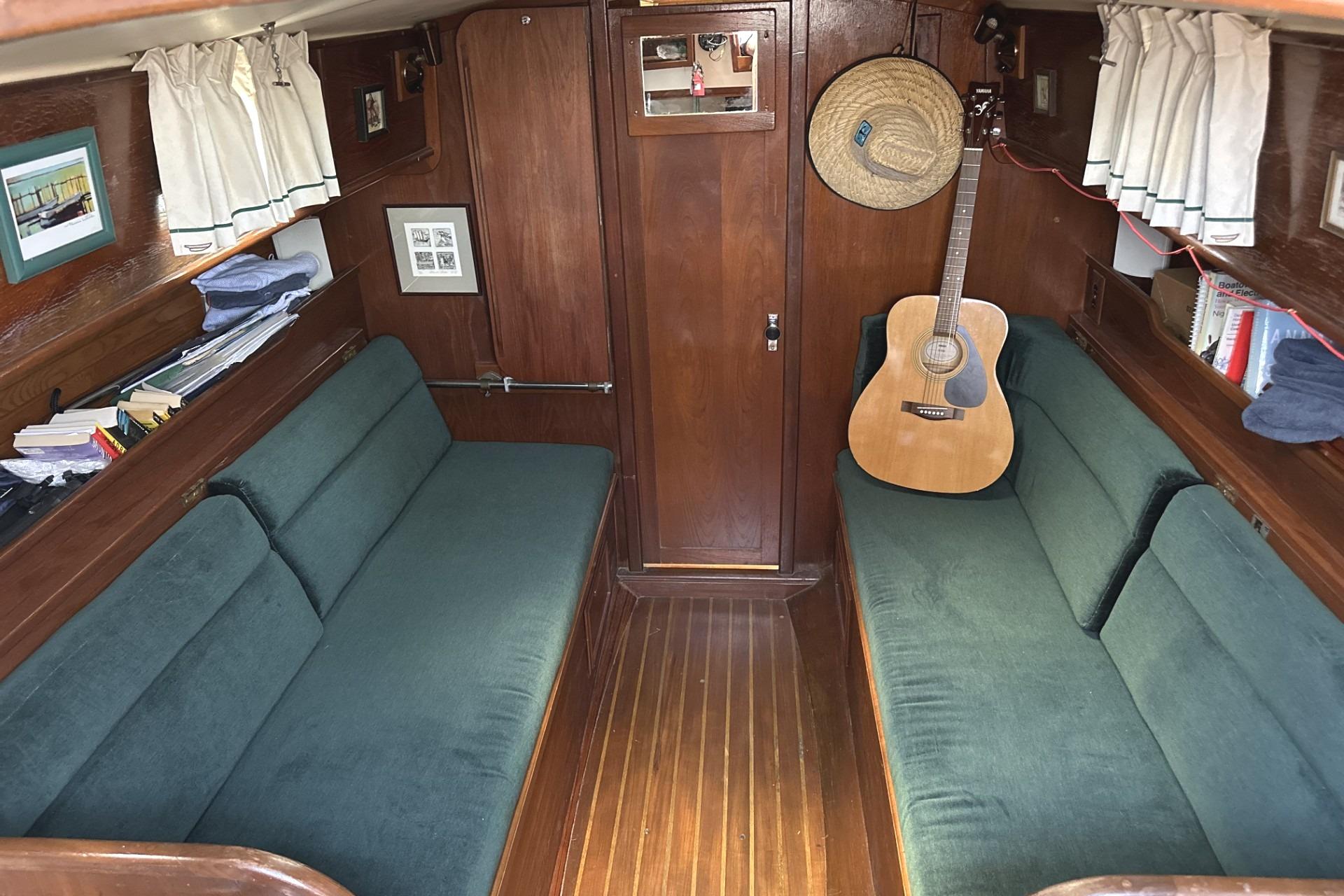 Interior of 1982 Cape Dory 30 sailboat with green seating and a guitar.