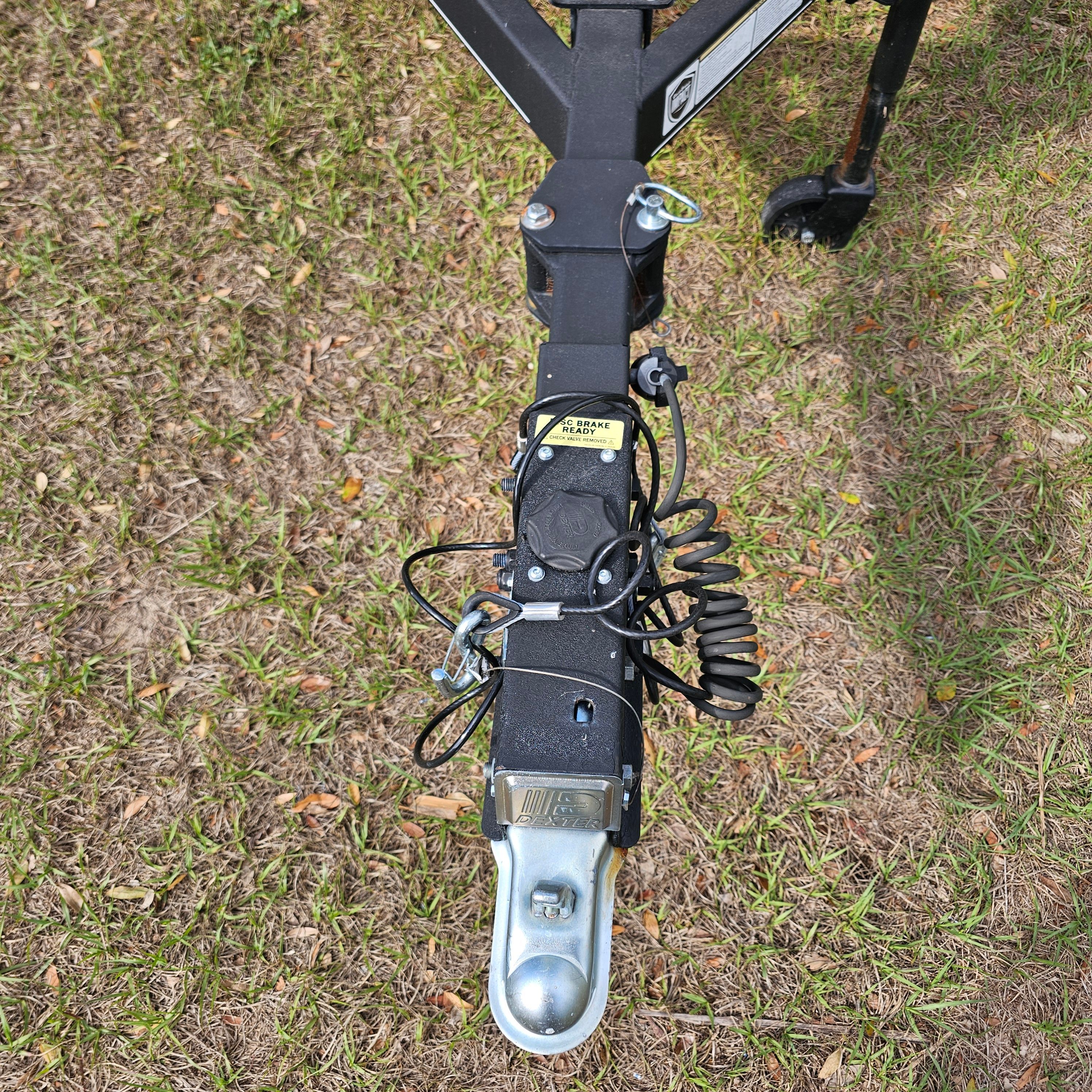 Trailer hitch of a 2024 Tahoe T18 on grass, featuring safety chains and wiring.