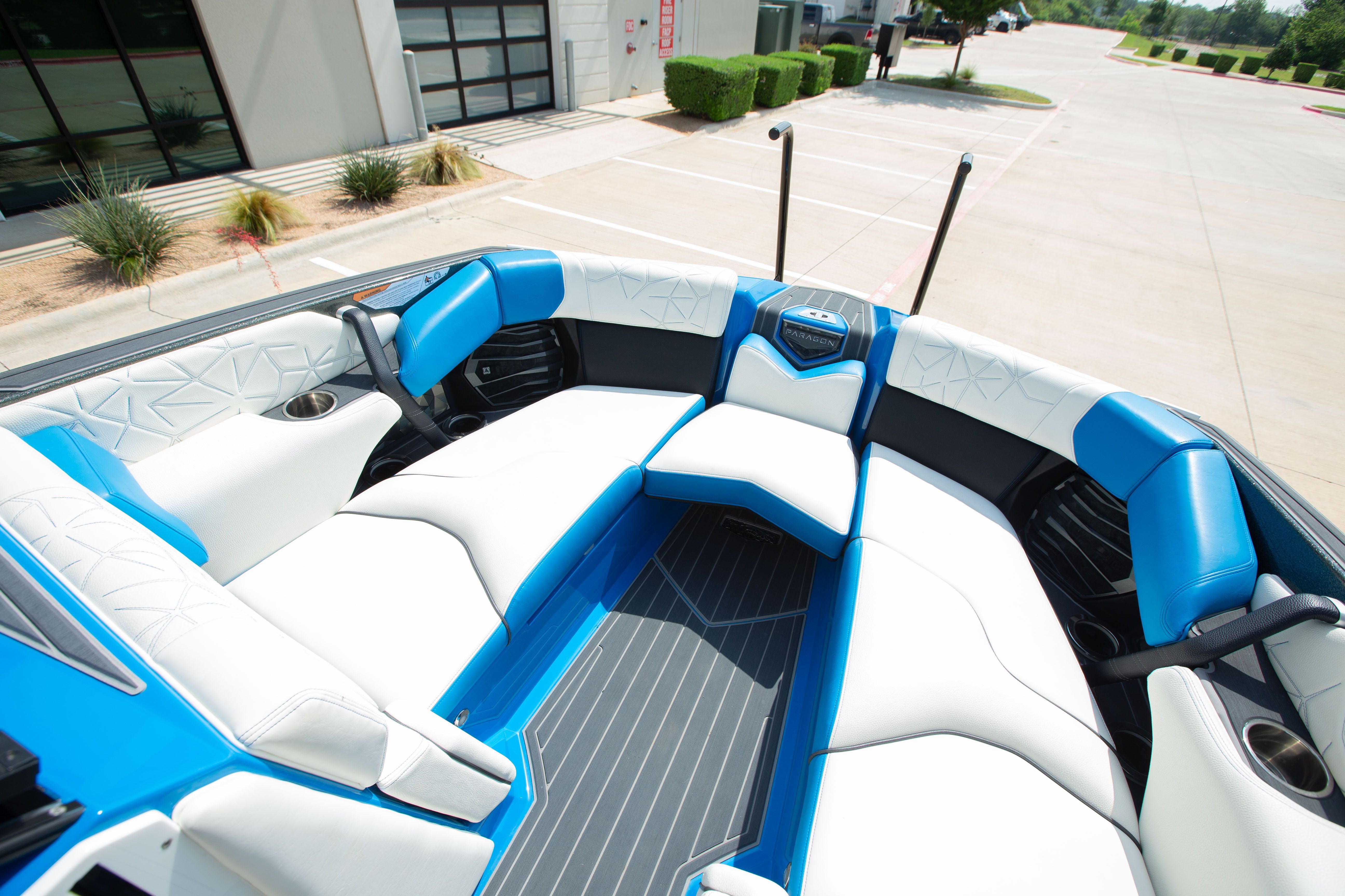 The boat features white and blue upholstery with modern patterns, parked in a lot.