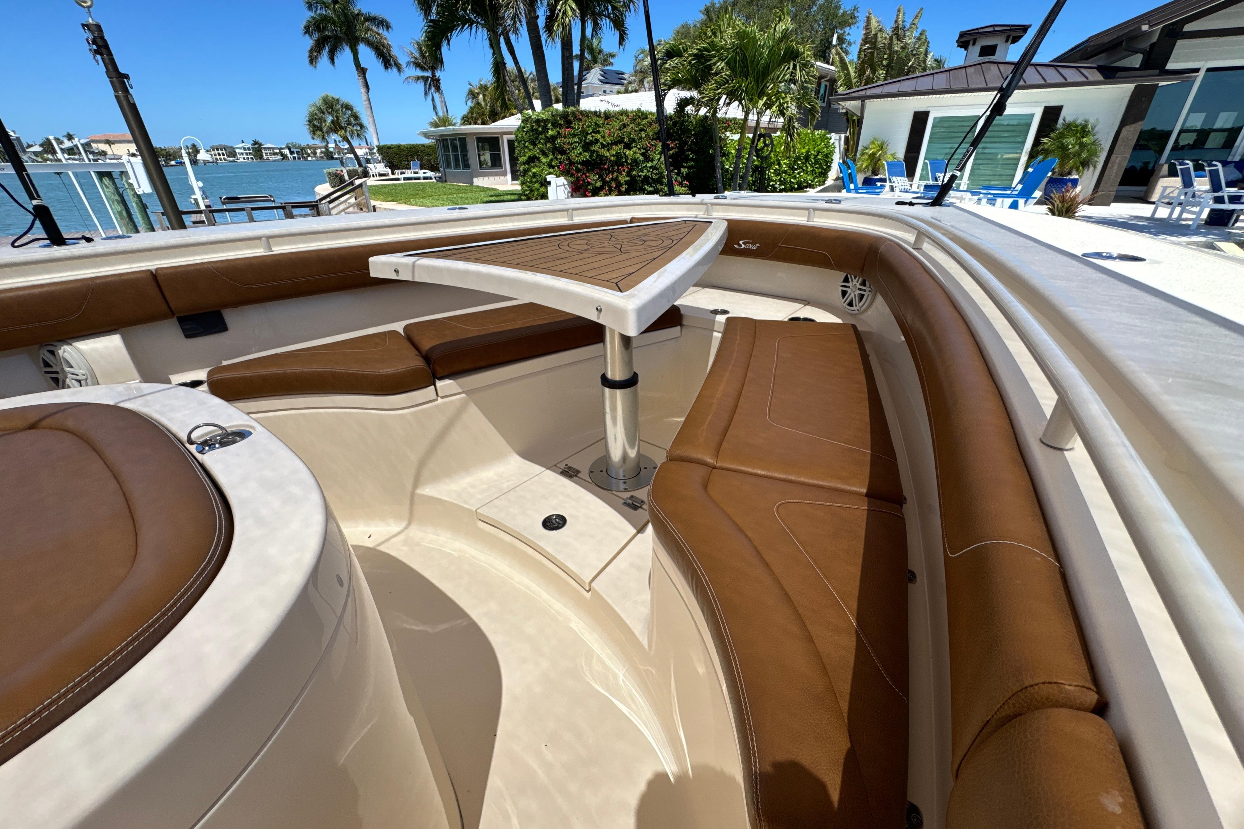 2018 Scout 355 LXF boat interior with brown seating and table, docked near waterfront homes.