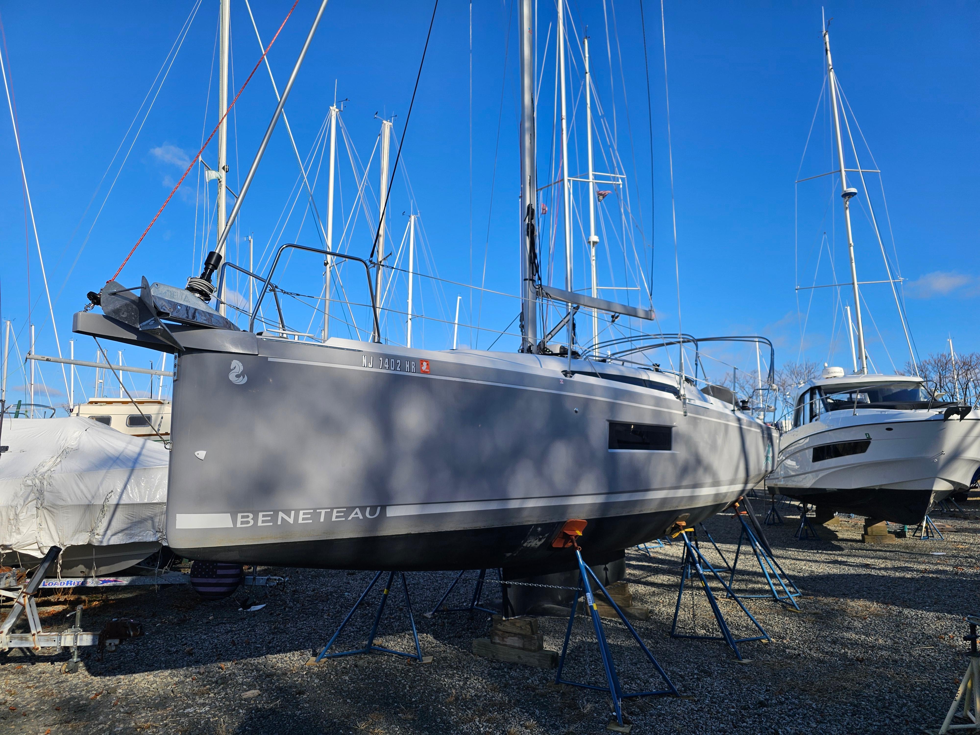 Beneteau Oceanis 30.1 sailboat, 2022 model, on stands in a marina under clear blue sky.
