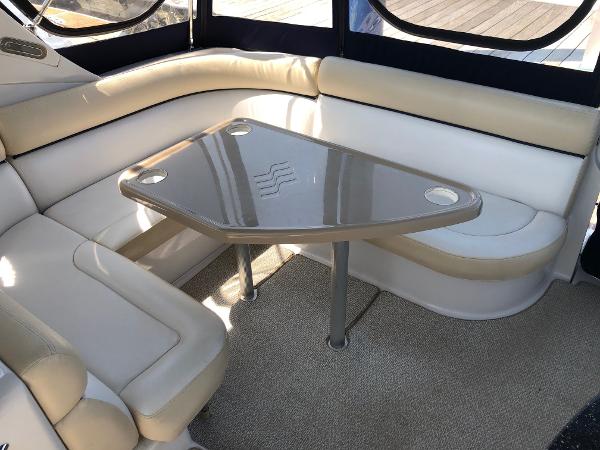 Interior of a 2008 Four Winns V338 with beige and white seating area and a table.