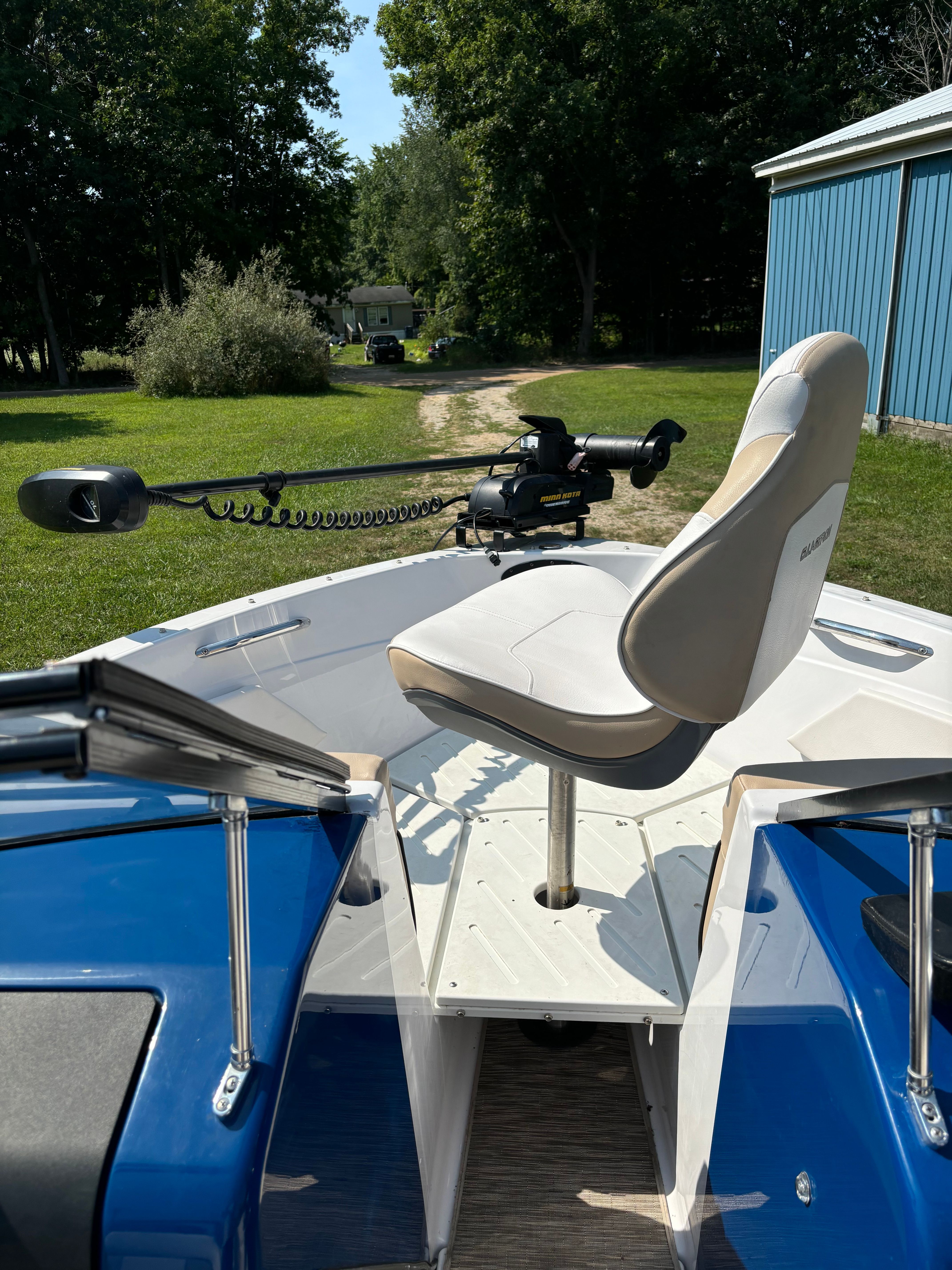 A Glastron GTSF 185 boat is on grass, surrounded by trees.