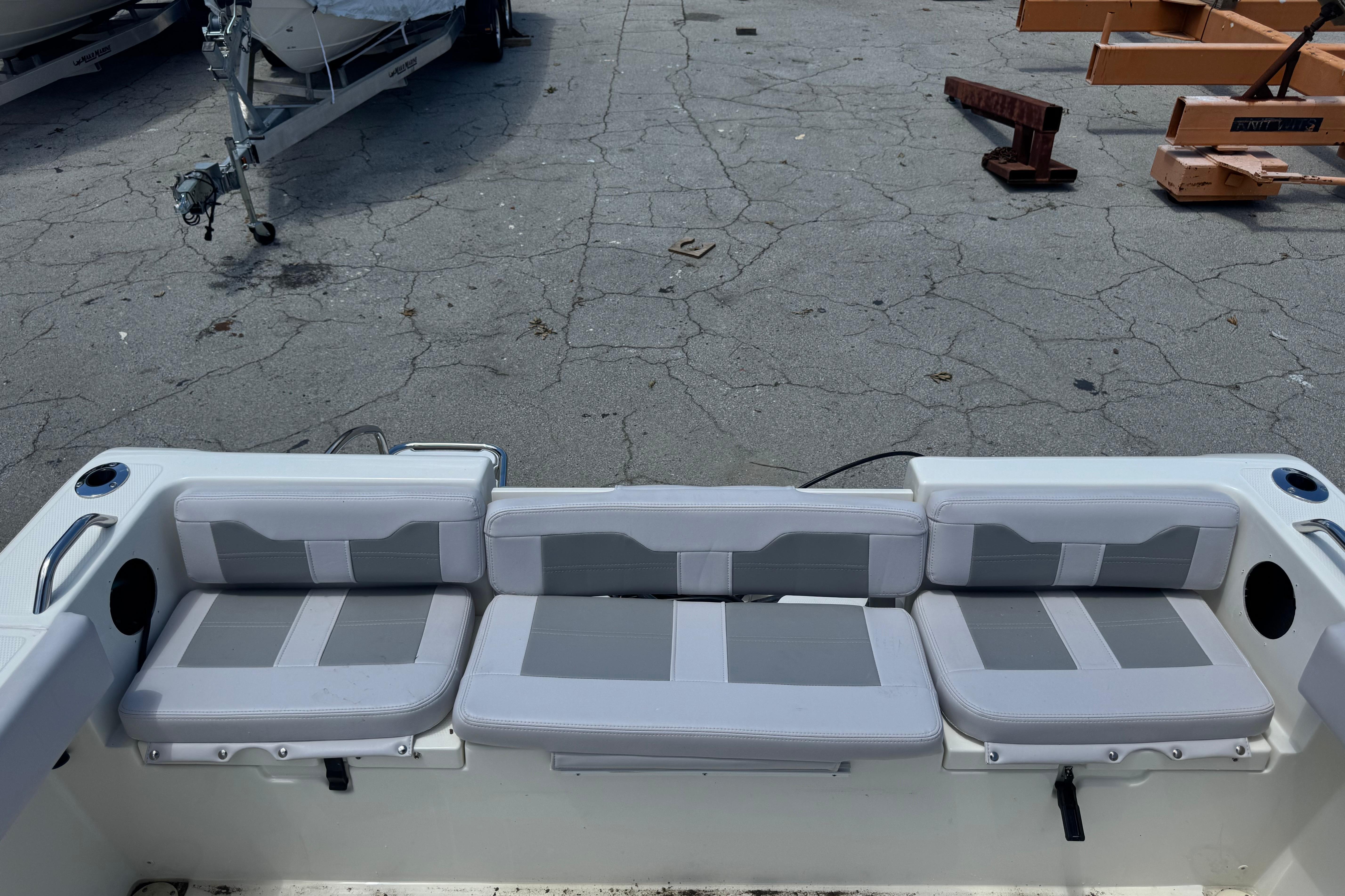 2026 Mako 214 Center Console boat with gray cushioned seating in a parking area.